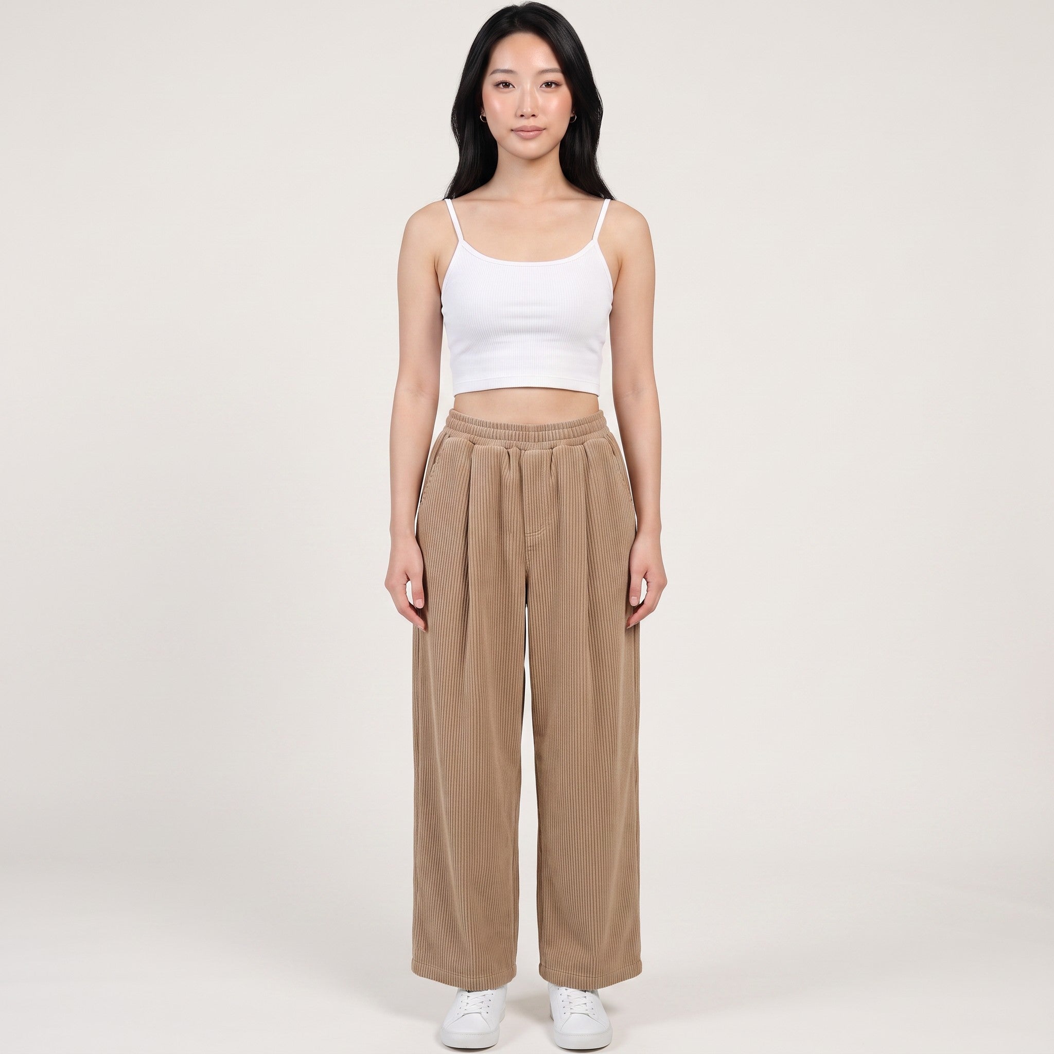 Model wearing Y2K Avenue beige wide-leg corduroy trousers with an elasticated waist, paired with a white cropped top