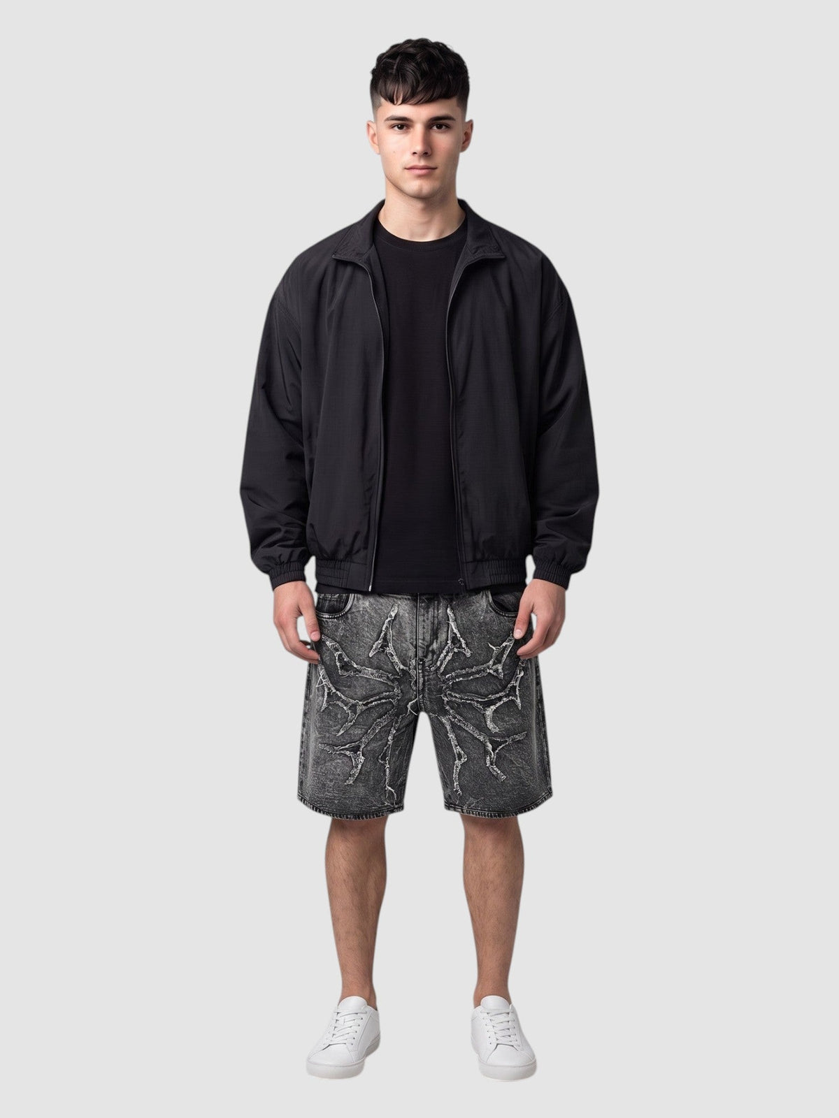 Short en denim délavé effet usé avec appliqué étoile épineuse et ourlets bruts effrangés, porté par un modèle homme.