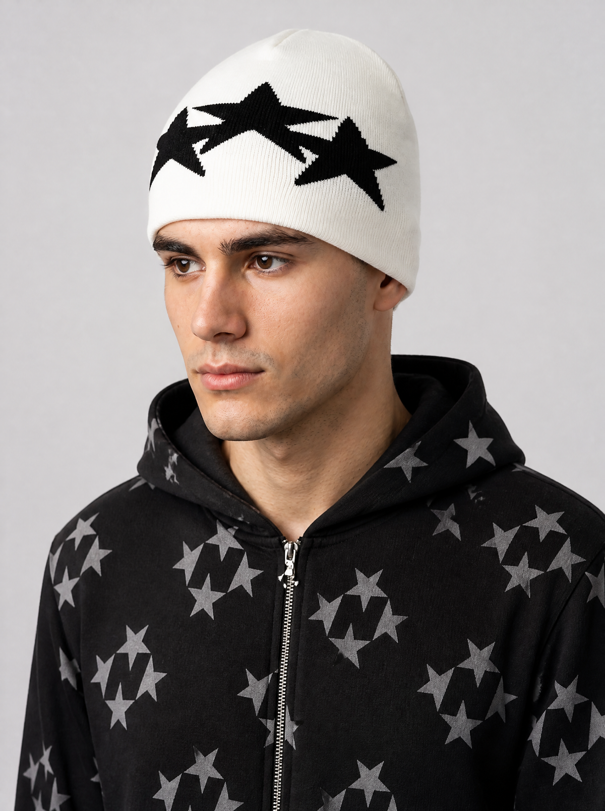 Autre vue | Bonnet blanc cassé à trois étoiles noires porté de trois quarts avec une veste zippée noire à motif étoiles grises | Variante : Blanc