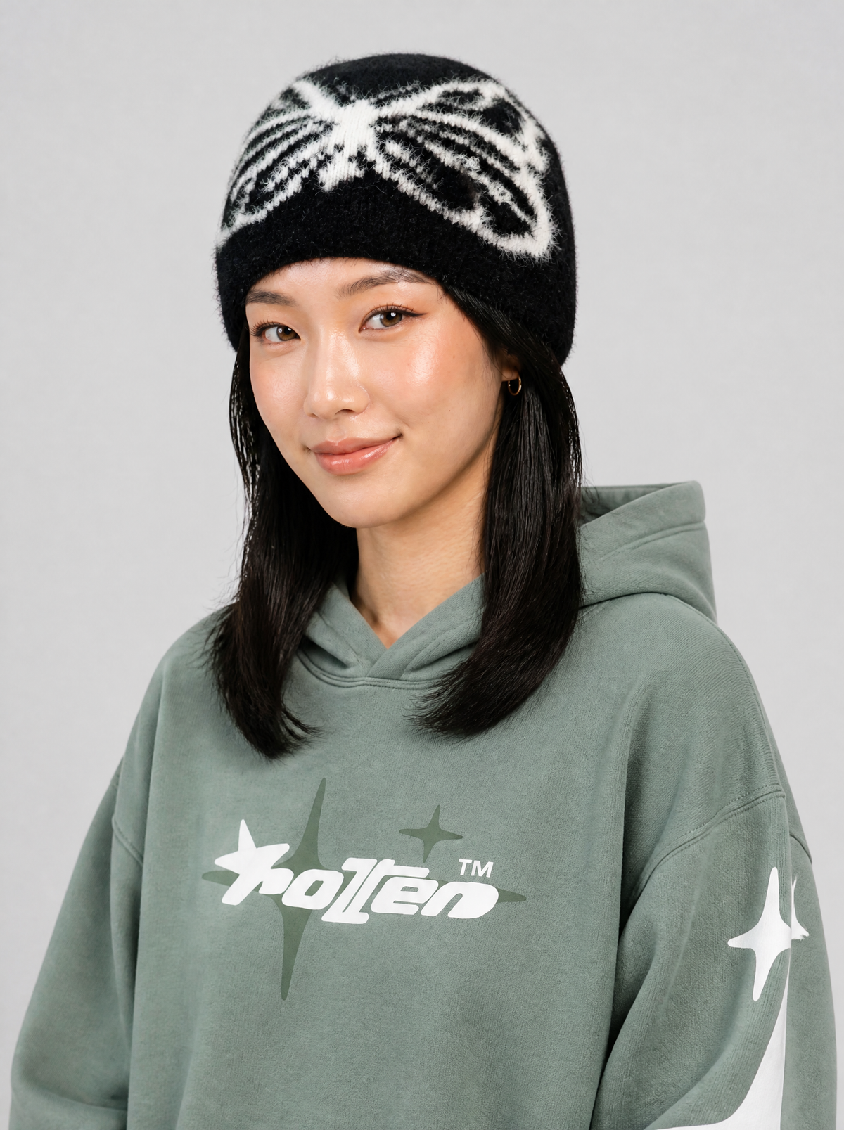 Autre vue | Bonnet noir duveteux à grand papillon blanc porté de trois quarts avec un hoodie vert sauge à logo blanc | Variante : Noir