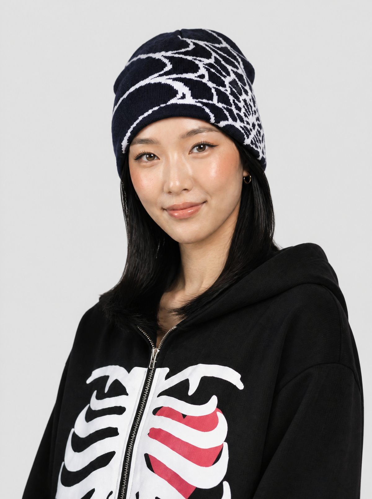 Autre vue | Femme portant le bonnet marine à toile d’araignée blanche en jacquard, vue de trois quarts, avec un sweat zippé squelette | Variante : Marine