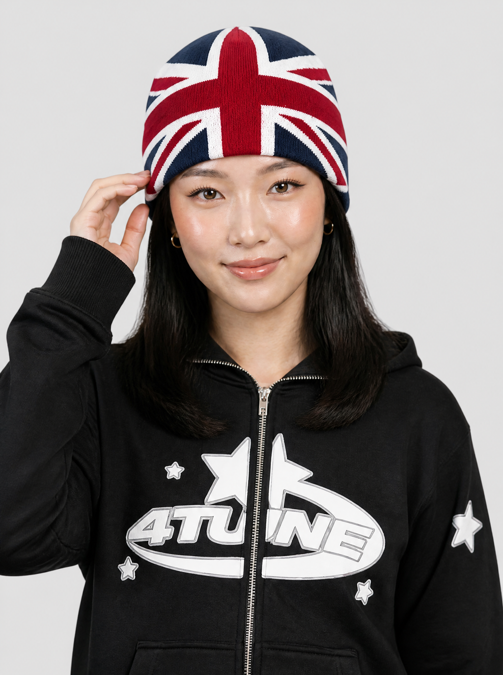 Autre vue | Femme de face, main sur son bonnet Union Jack marine et rouge, sweat zippé noir à logo étoilé blanc | Variante : Marine