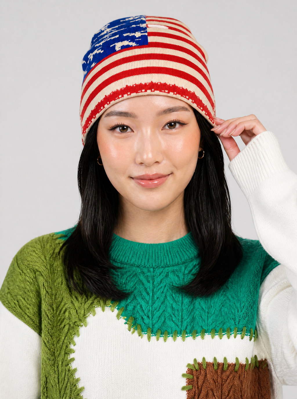 Autre vue | Femme de face, main sur son bonnet rayé rouge et crème à canton bleu étoilé, pull blanc patchwork vert | Variante : Rouge
