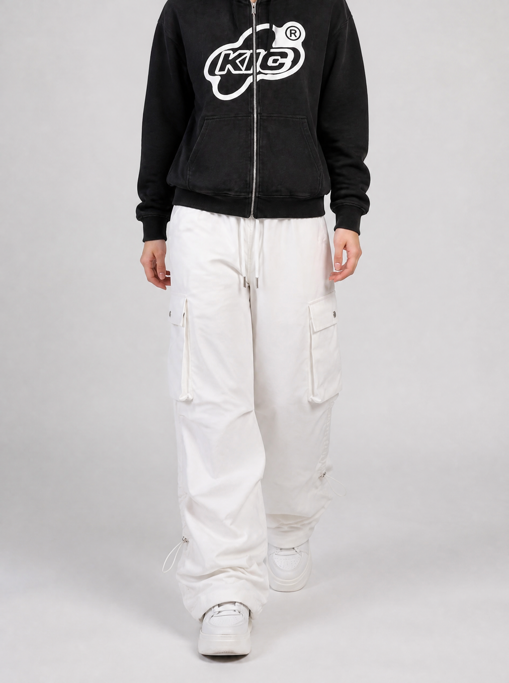 Autre vue | Femme qui marche en cargo parachute blanc large à cordons de serrage, sweat zippé noir à logo blanc