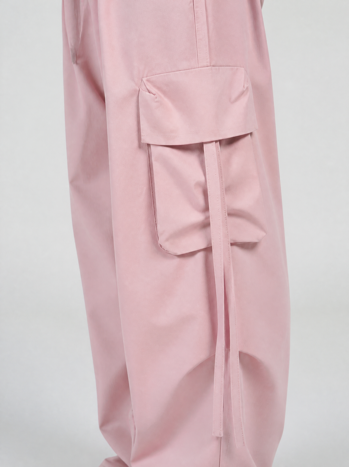 Photo détail | Gros plan sur la poche cargo à rabat et les sangles pendantes du pantalon rose pastel