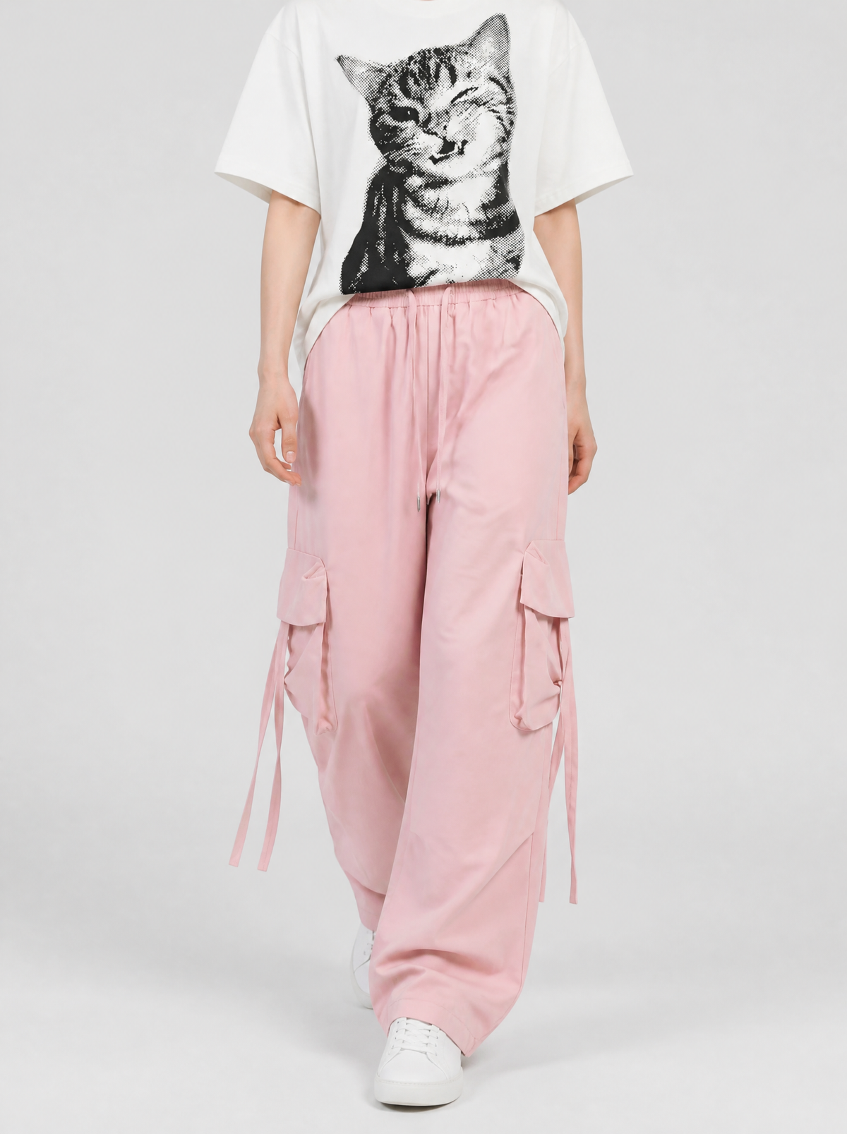Autre vue | Femme qui marche en cargo large rose pâle à sangles pendantes, t-shirt blanc à chat qui fait un clin d'oeil