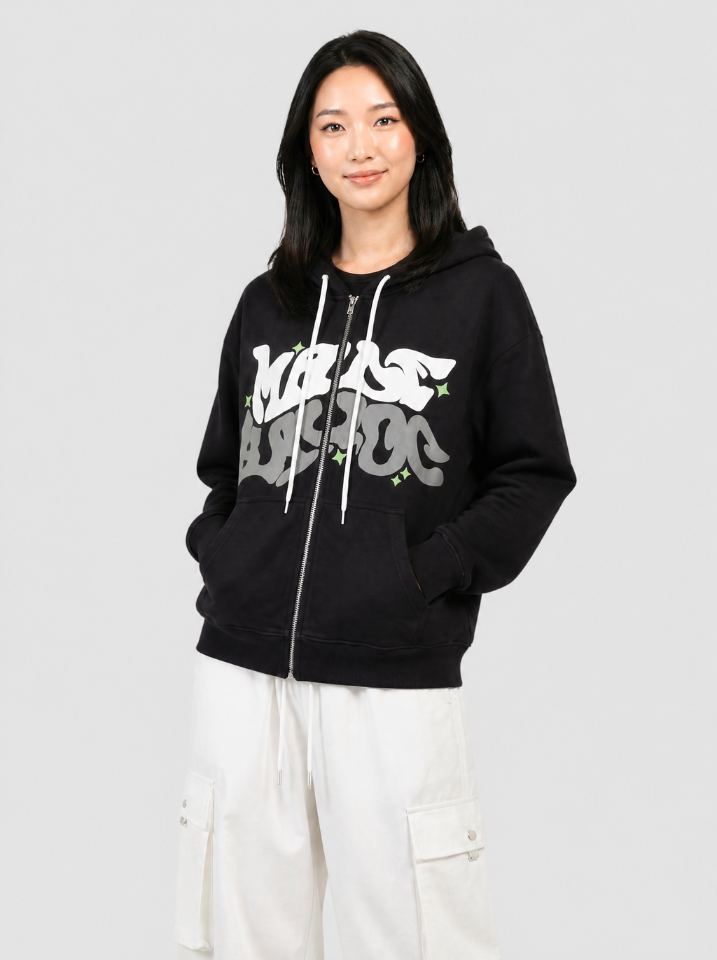 Autre vue | Sweat zippé noir à lettrage graffiti blanc et gris porté de trois quarts avec un pantalon cargo parachute blanc | Variante : Noir