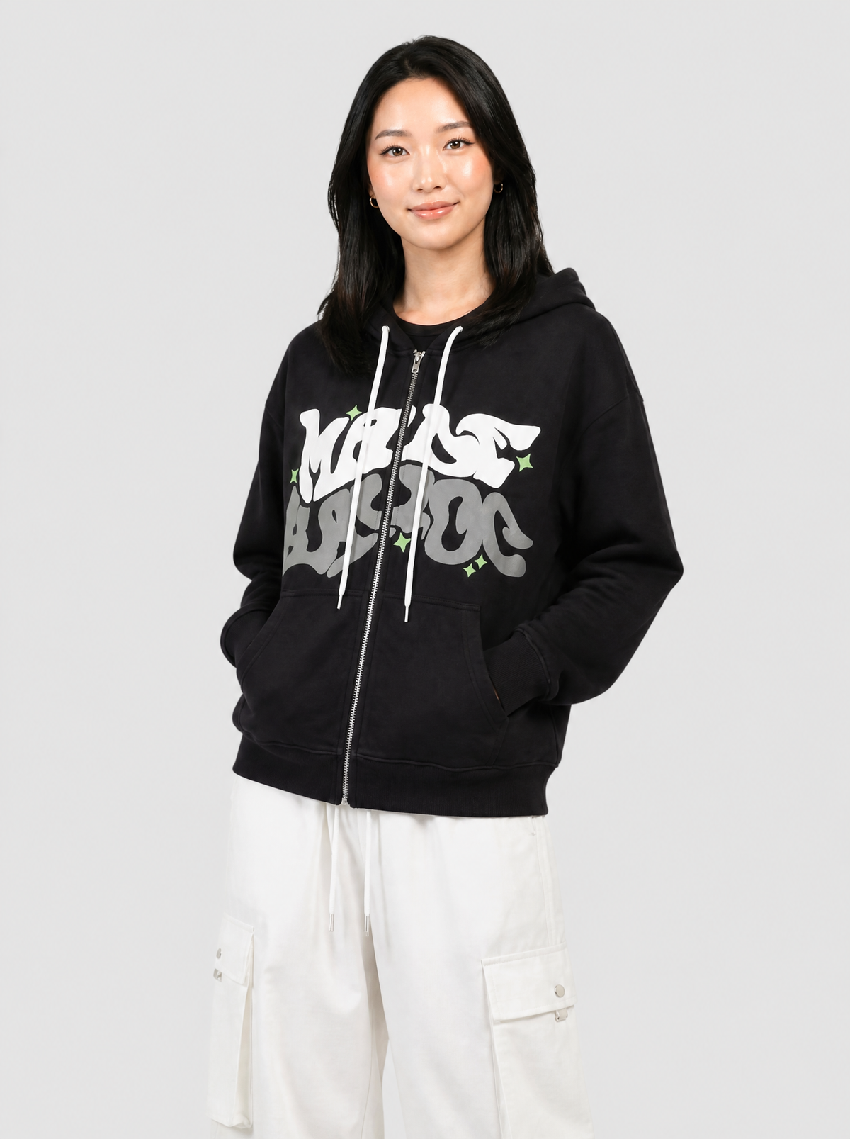 Autre vue | Sweat zippé noir à lettrage graffiti blanc et gris porté de trois quarts avec un pantalon cargo parachute blanc | Variante : Noir