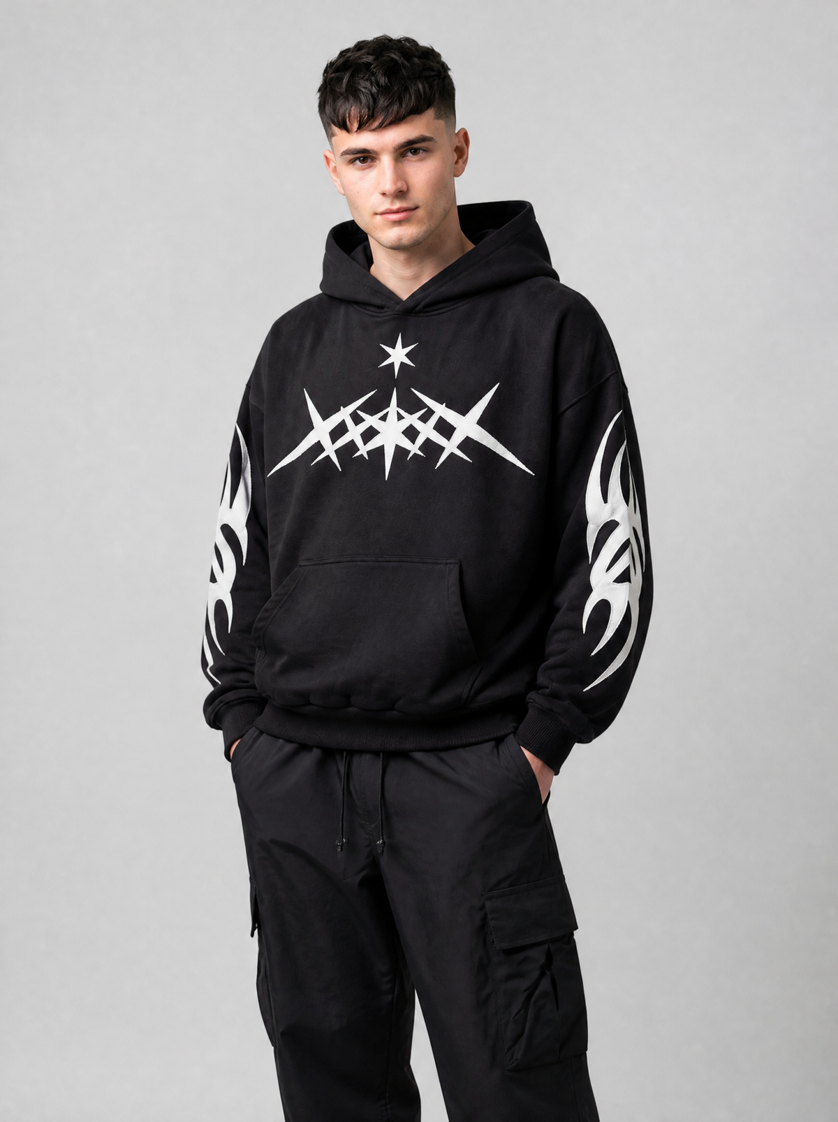 Autre vue | Hoodie noir oversize à motif étoiles pointues blanc et manches tribales porté de trois quarts avec un cargo noir