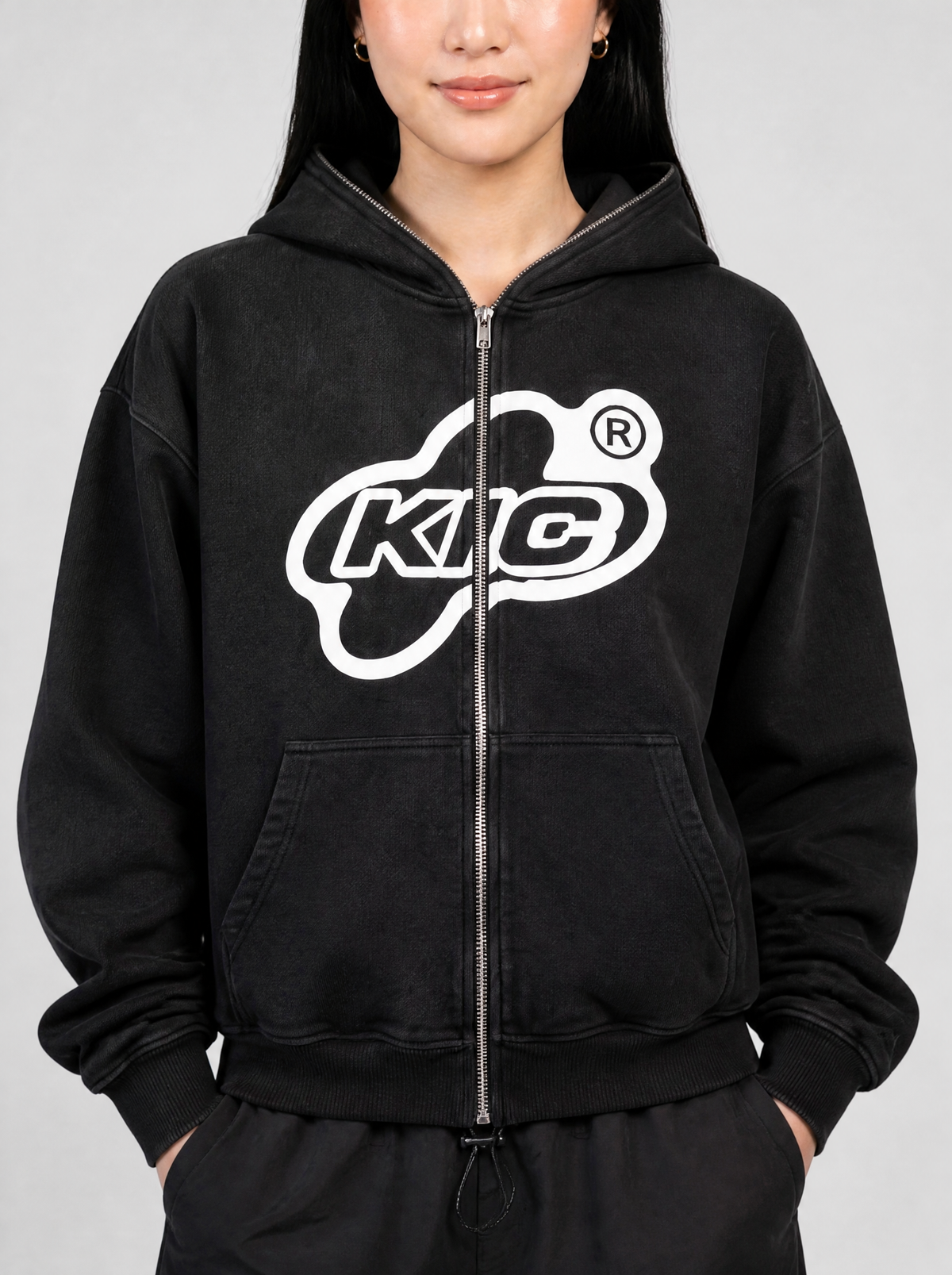 Photo détail | Gros plan sur le logo ovale blanc KIC coupé par le zip argenté et le molleton délavé du hoodie noir | Variante : Noir