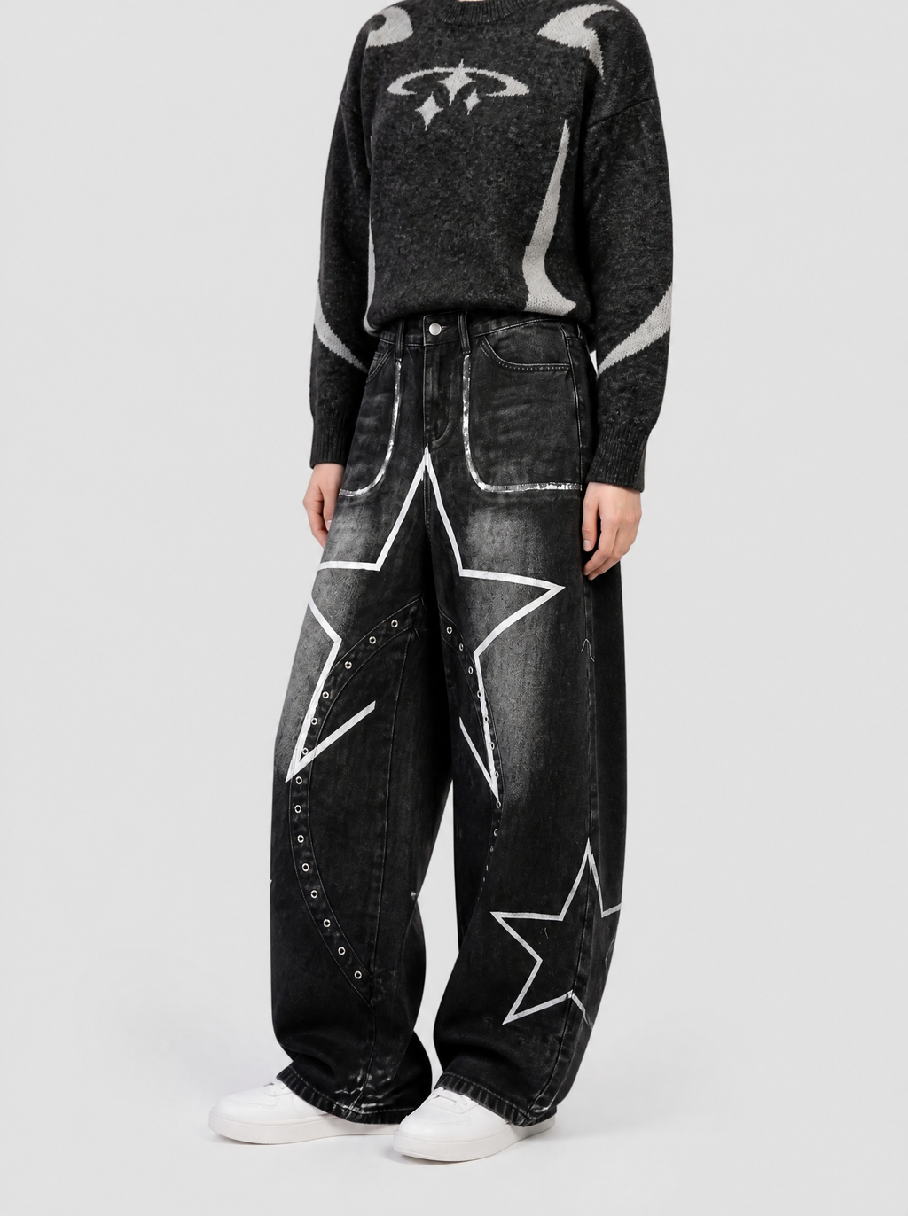 Autre vue | Jean baggy noir délavé à grande étoile blanche et œillets argentés, porté de trois quarts avec un pull noir duveteux à motifs gris
