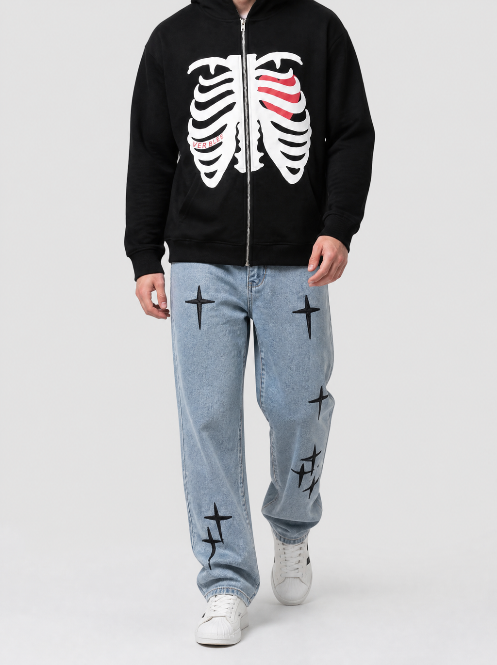 Autre vue | Homme marchant de face en jean bleu clair à croix gothiques noires brodées, assorti à un hoodie zippé noir imprimé squelette