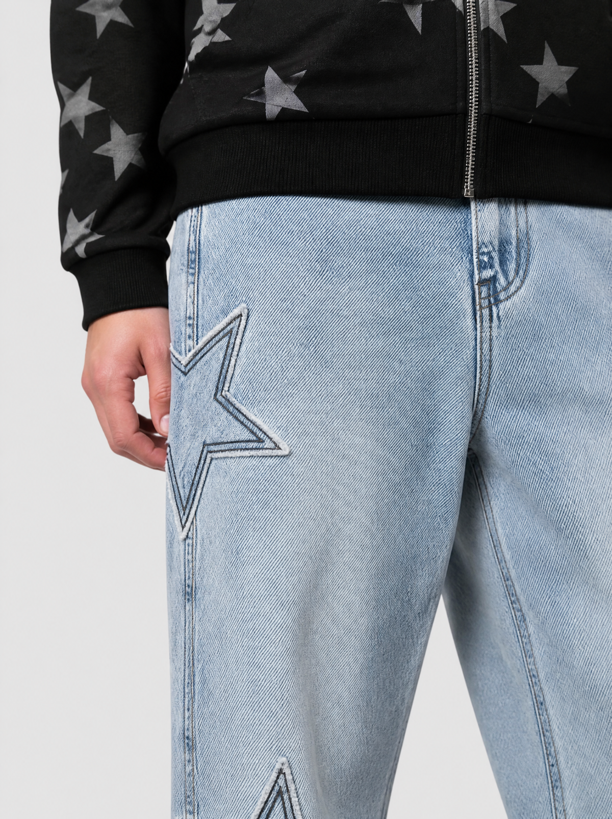 Photo détail | Gros plan sur une étoile en denim aux bords effilochés et surpiqûre foncée, cousue sur la jambe du jean bleu clair | Variante : Bleu