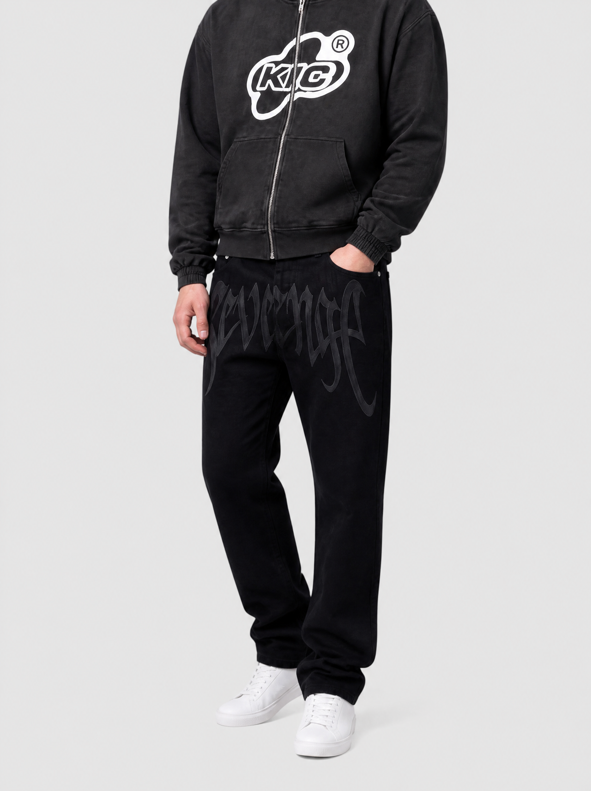 Autre vue | Jean noir droit imprimé Revenge en lettres gothiques grises, porté de trois quarts face avec un hoodie zippé noir à logo blanc