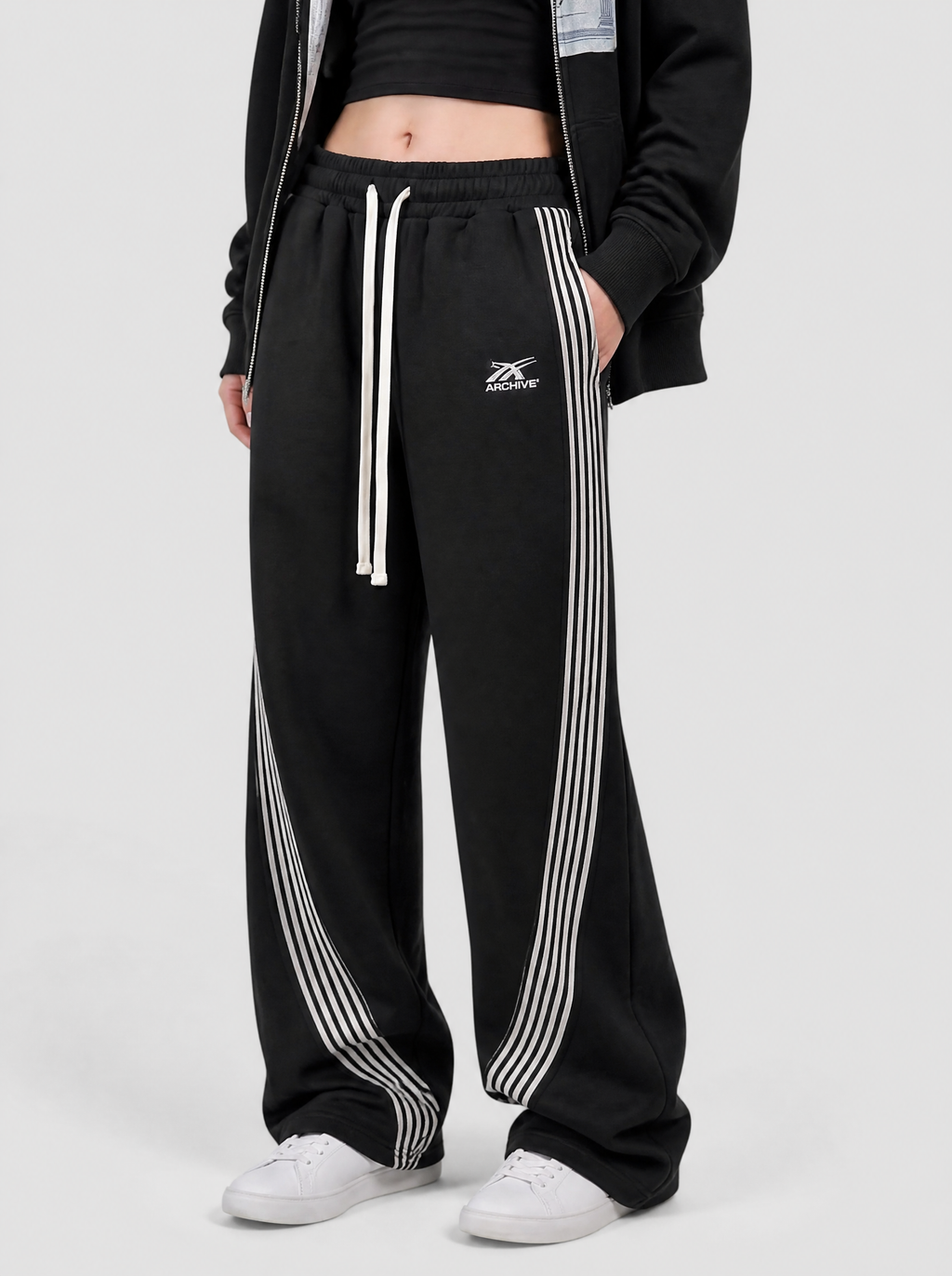Photo détail | Gros plan sur le cordon blanc, le petit logo brodé et les bandes blanches courbées du jogging noir | Variante : Noir