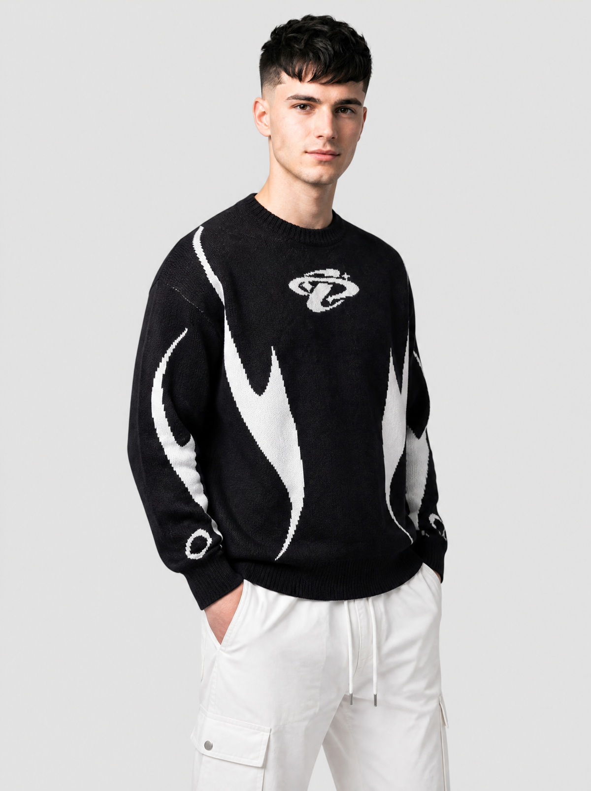 Autre vue | Pull en maille noir à flammes blanches et emblème orbital, porté de trois quarts face avec un pantalon cargo parachute blanc | Variante : Noir