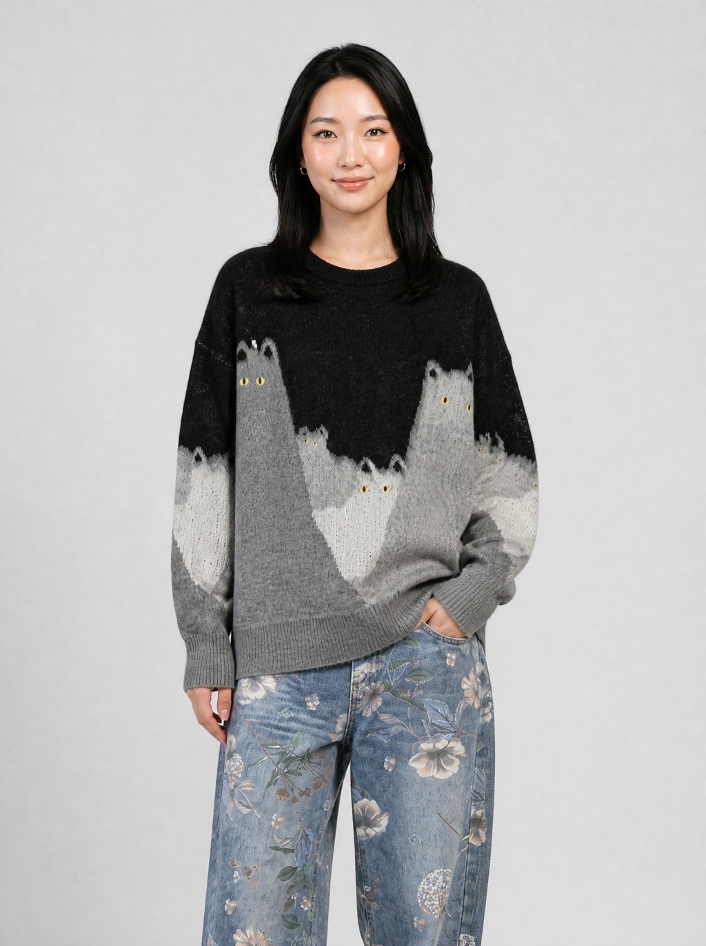 Autre vue | Femme de face en pull oversize noir et gris à motif chats, associé à un jean large bleu délavé à imprimé floral | Variante : Noir