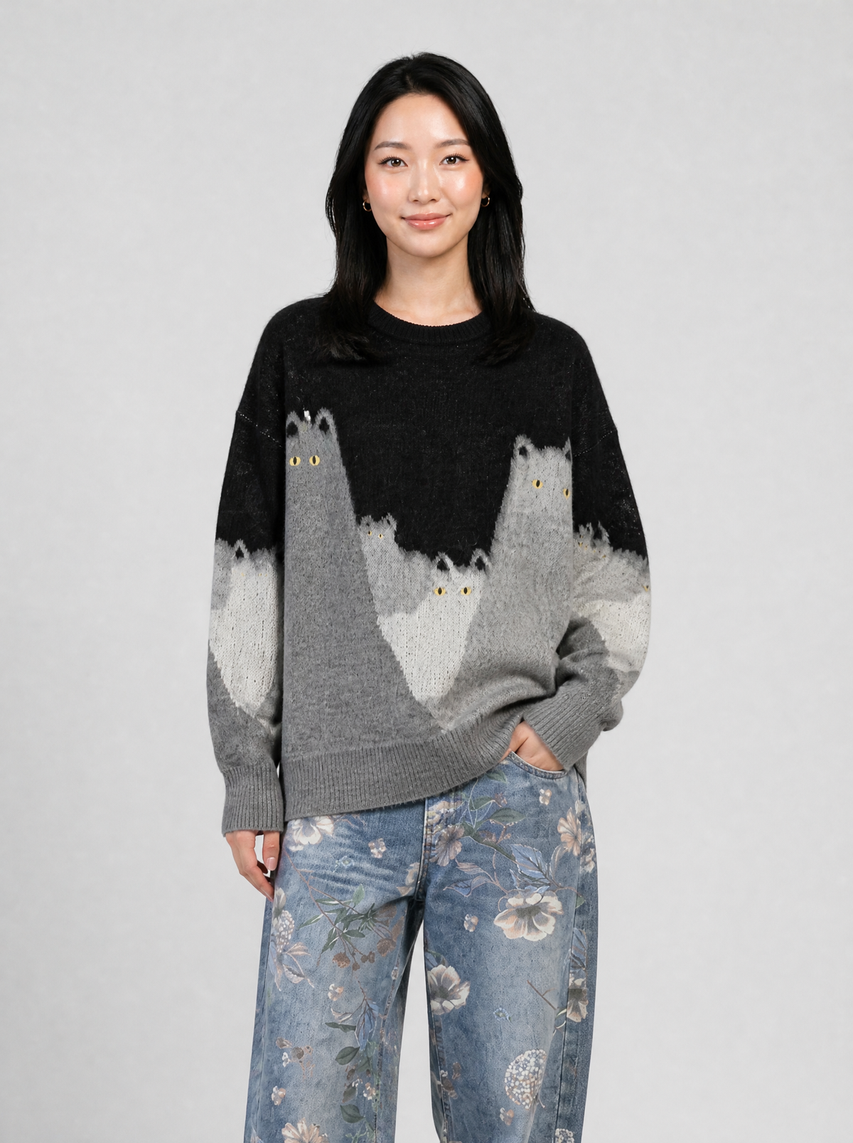 Autre vue | Femme de face en pull oversize noir et gris à motif chats, associé à un jean large bleu délavé à imprimé floral | Variante : Noir