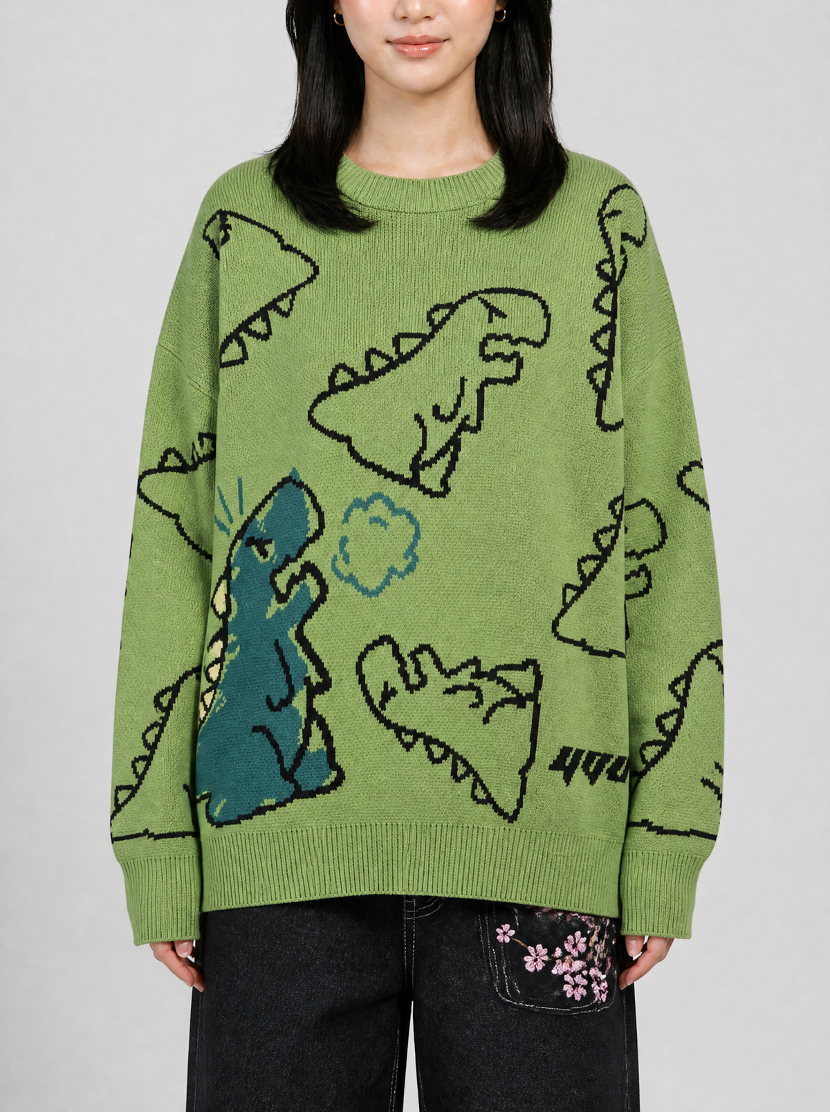 Photo détail | Gros plan sur la maille jacquard du pull vert : dinosaures dessinés au trait noir et grand dinosaure bleu canard | Variante : Vert