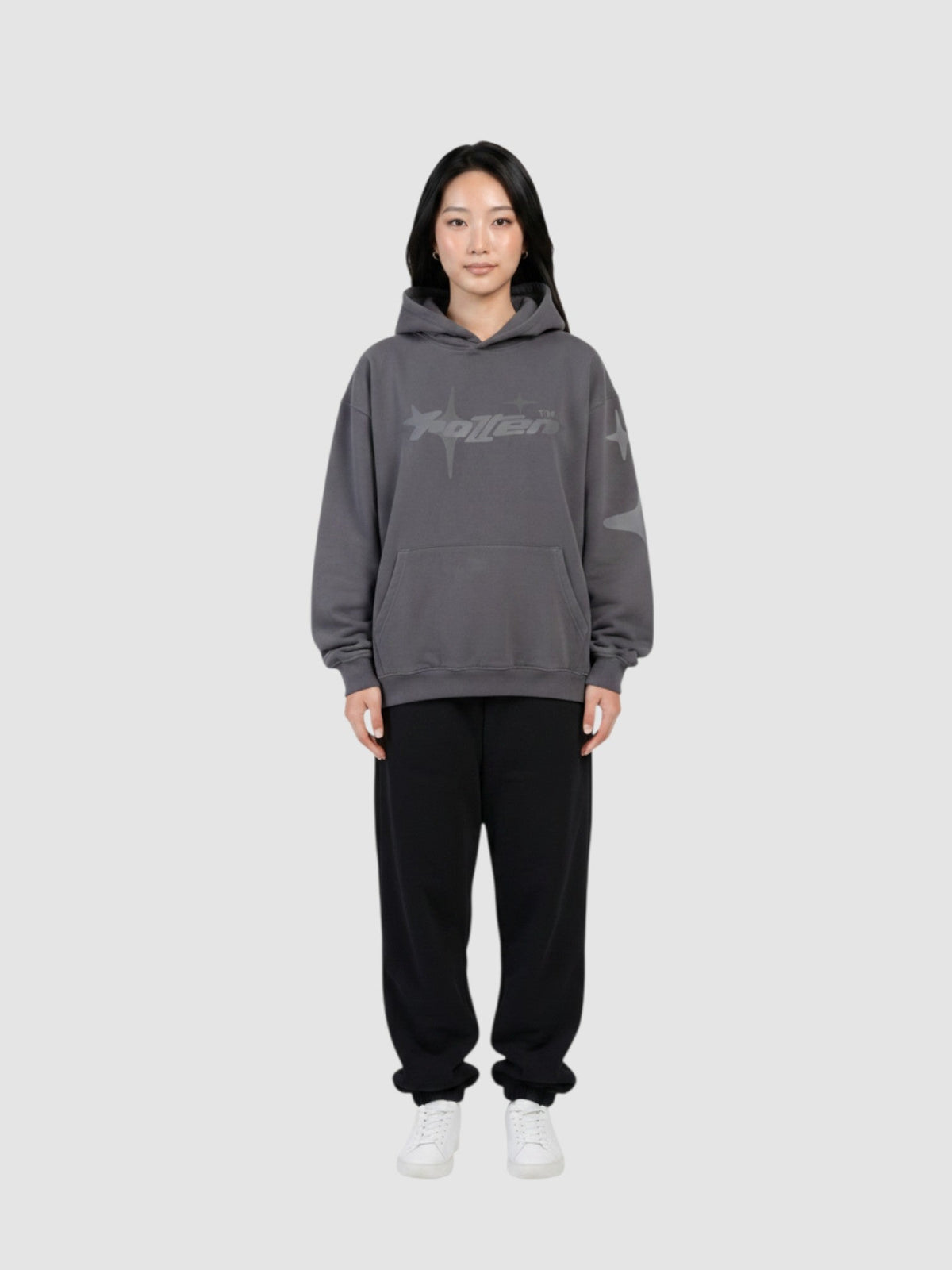 Hoodie oversize gris avec graphisme étoile imprimé, porté par un modèle avec un jogging noir et des baskets blanches.