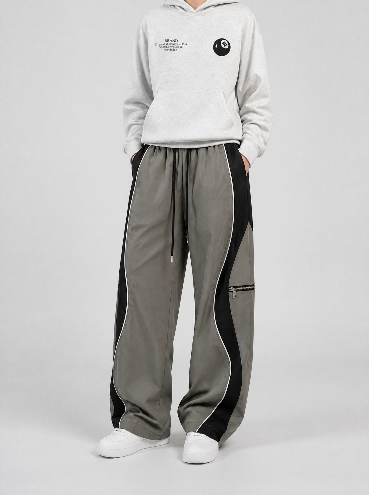 Autre vue | Pantalon large gris olive à bandes latérales noires ondulées et passepoil blanc, porté de trois quarts avec un hoodie gris chiné