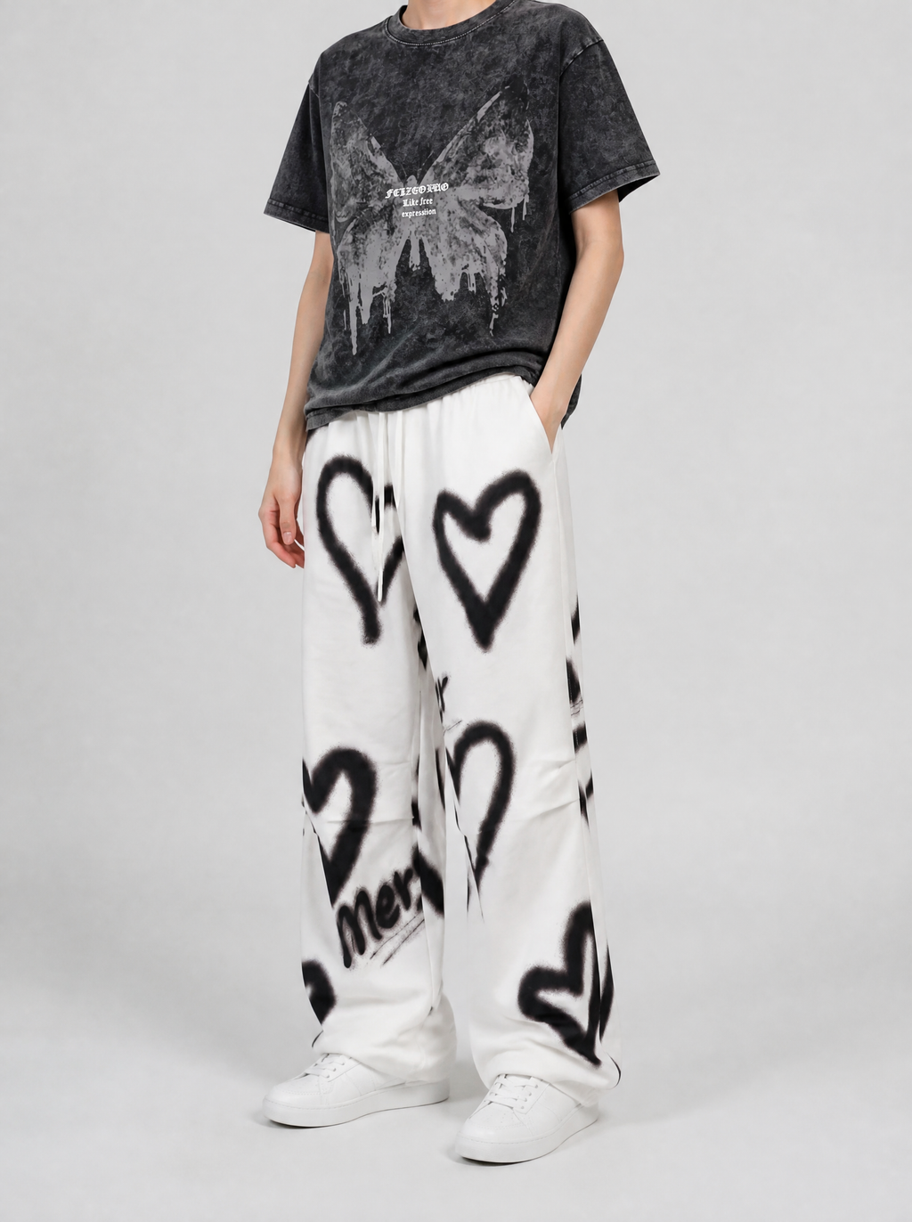 Autre vue | Pantalon jogging blanc large à cœurs noirs effet bombe graffiti, porté de trois quarts par une femme avec un t-shirt délavé noir