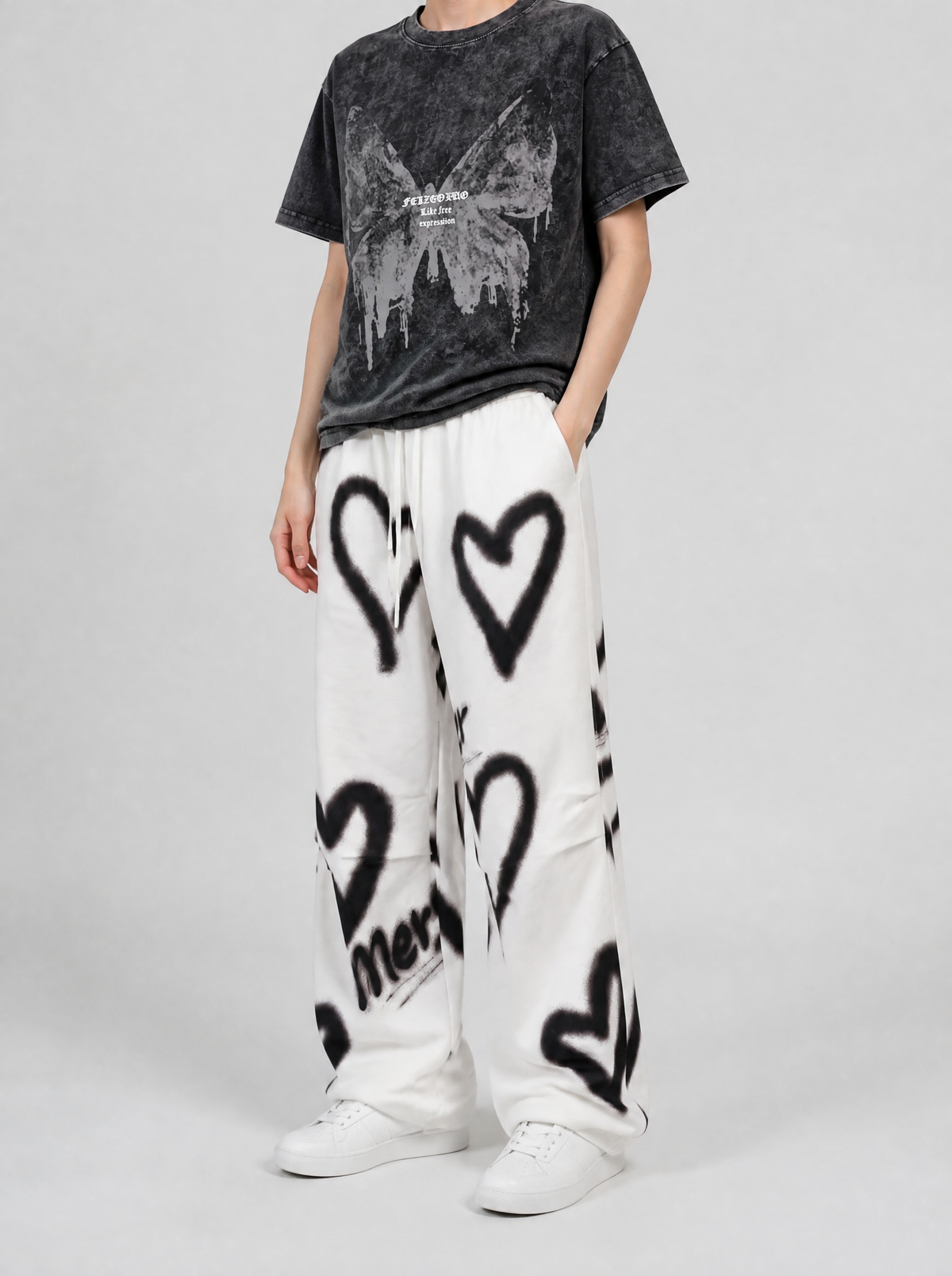 Autre vue | Pantalon jogging blanc large à cœurs noirs effet bombe graffiti, porté de trois quarts par une femme avec un t-shirt délavé noir