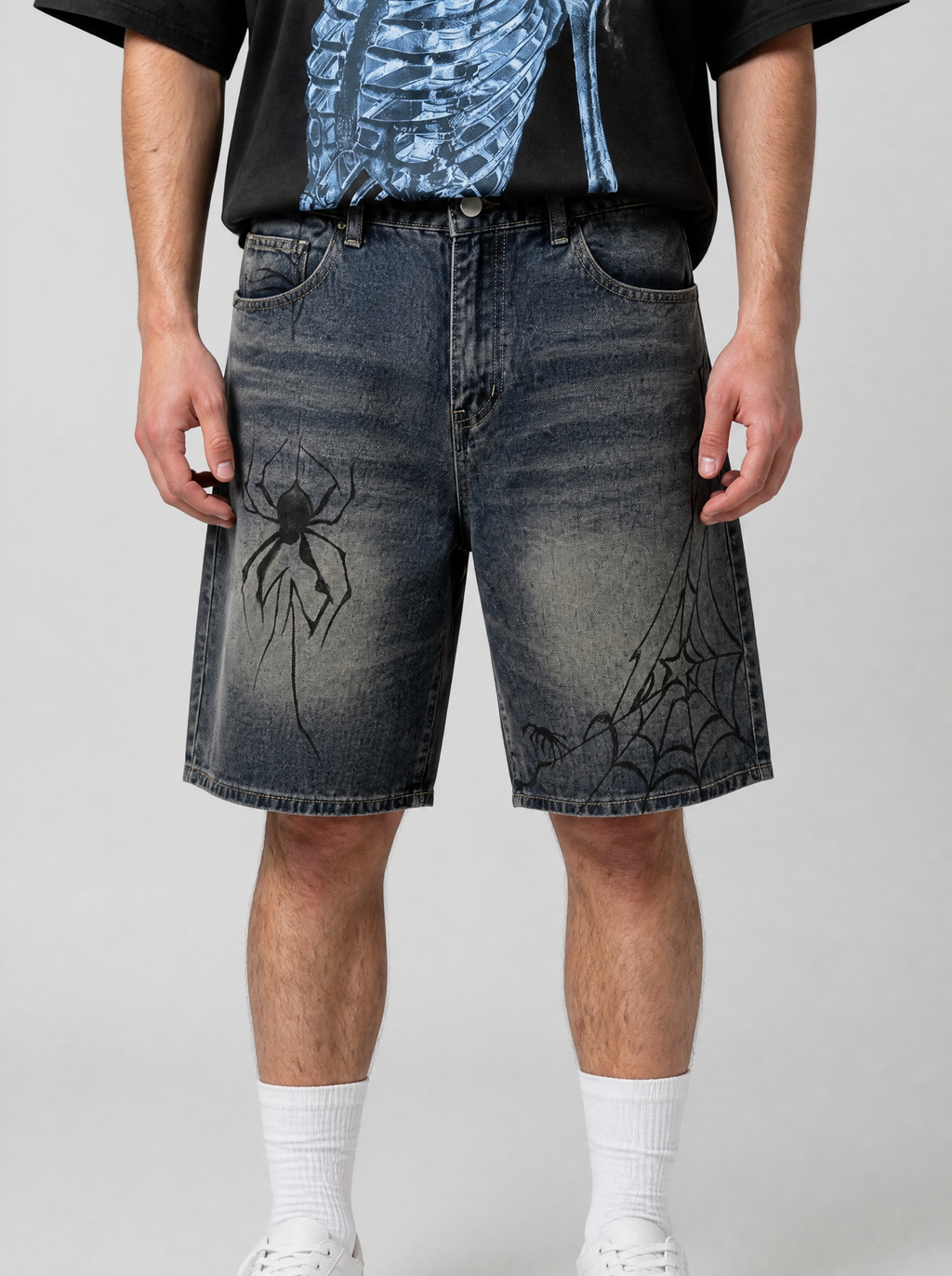 Photo détail | Gros plan sur le jean délavé du short : araignée noire sur la cuisse et toile d’araignée près de l’ourlet