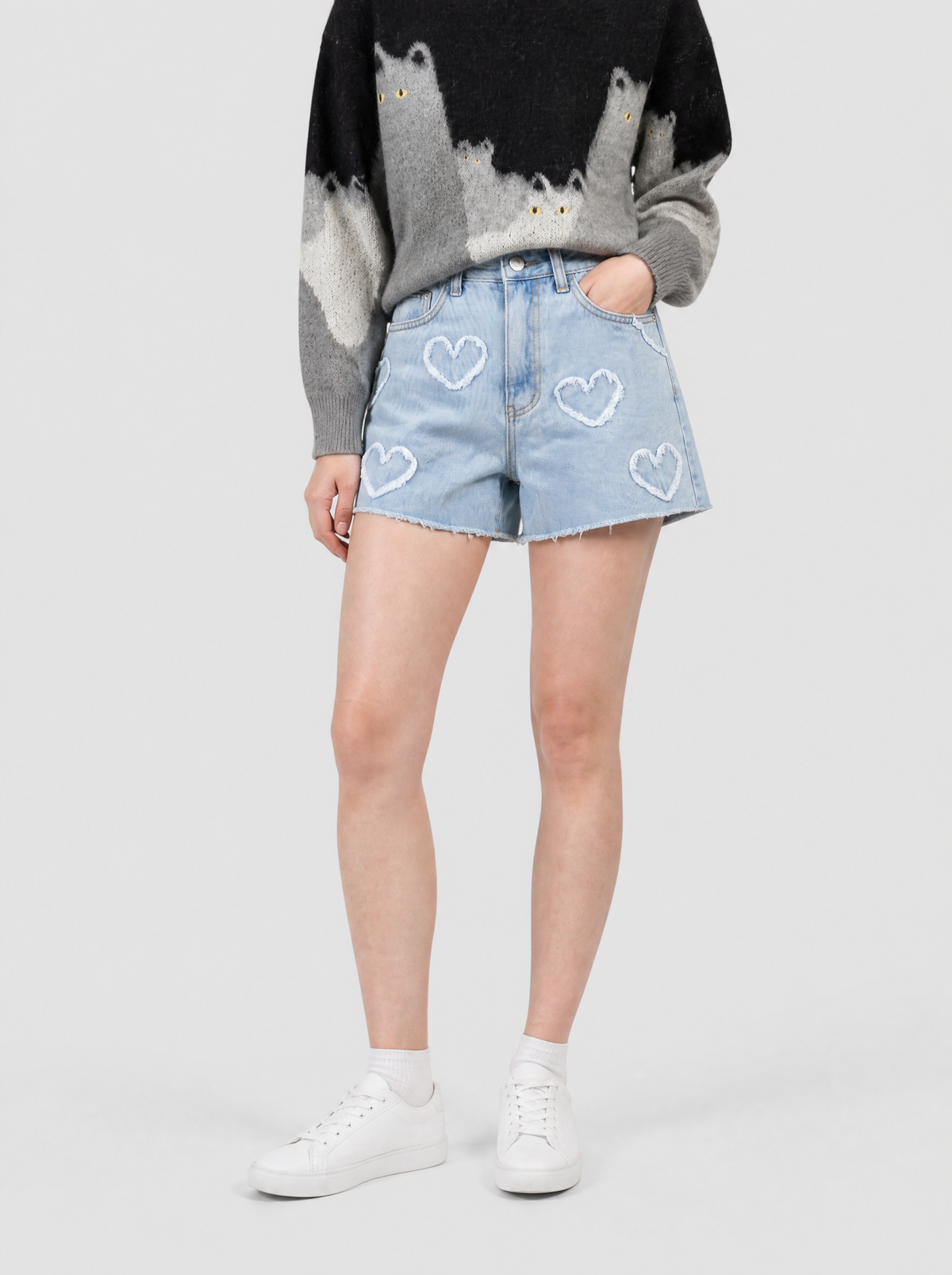 Autre vue | Short en jean bleu clair taille haute à cœurs effilochés blancs et ourlet brut, porté de trois quarts avec un pull chat