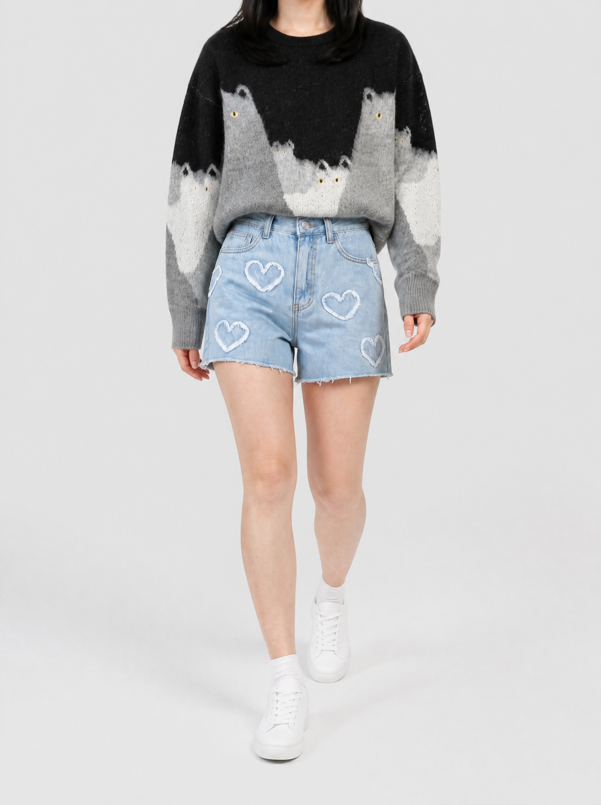 Autre vue | Femme marchant de face en short en jean bleu clair à cœurs blancs effilochés, portée avec un pull noir et gris à chats