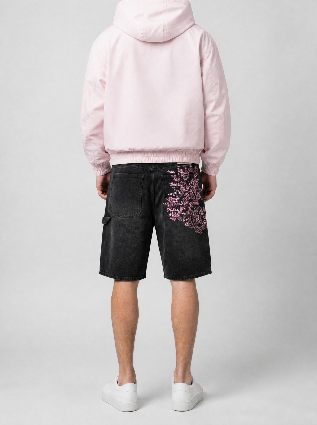 Autre vue | Vue de dos du short en jean noir brodé de fleurs de cerisier roses sur la poche arrière droite, porté avec une veste rose
