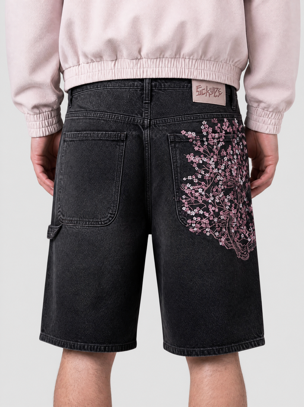 Photo détail | Gros plan sur la broderie de fleurs de cerisier roses et blanches sur la poche arrière du short en jean noir