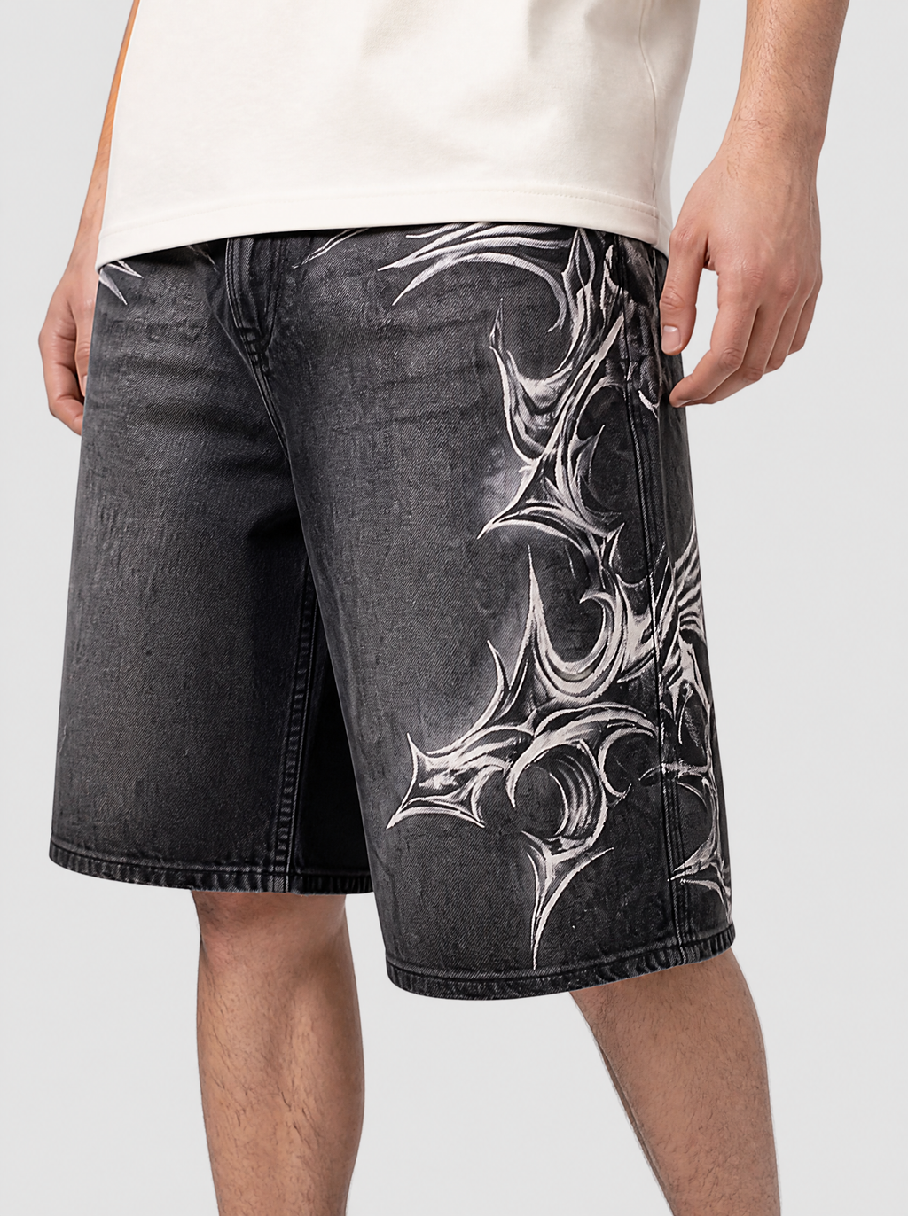Photo détail | Gros plan sur le motif tribal épineux blanc aérographié sur la cuisse du short en jean noir délavé