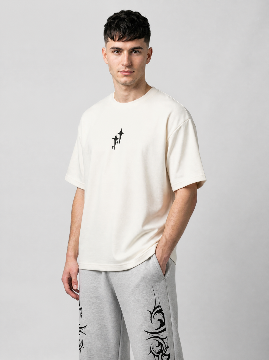 Autre vue | T-shirt oversize crème à petit motif d’étoiles noires au centre, porté de trois quarts avec un jogging tribal gris | Variante : Blanc
