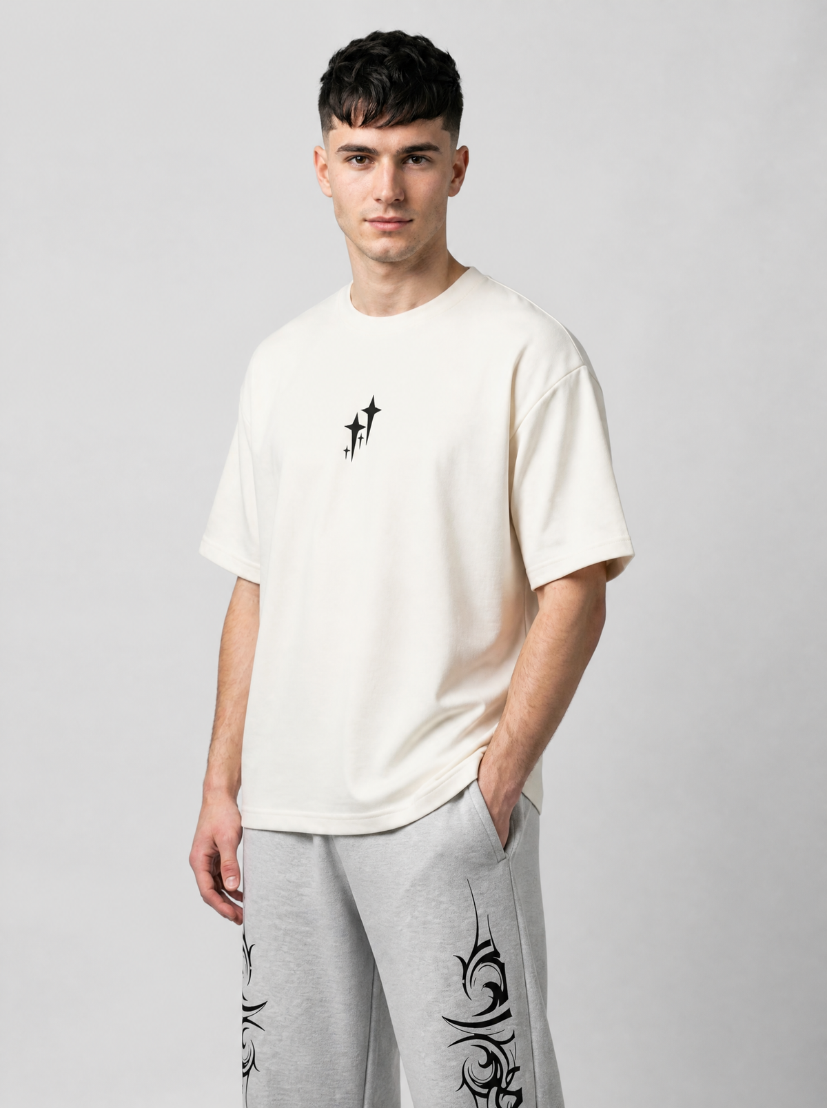 Autre vue | T-shirt oversize crème à petit motif d’étoiles noires au centre, porté de trois quarts avec un jogging tribal gris | Variante : Blanc