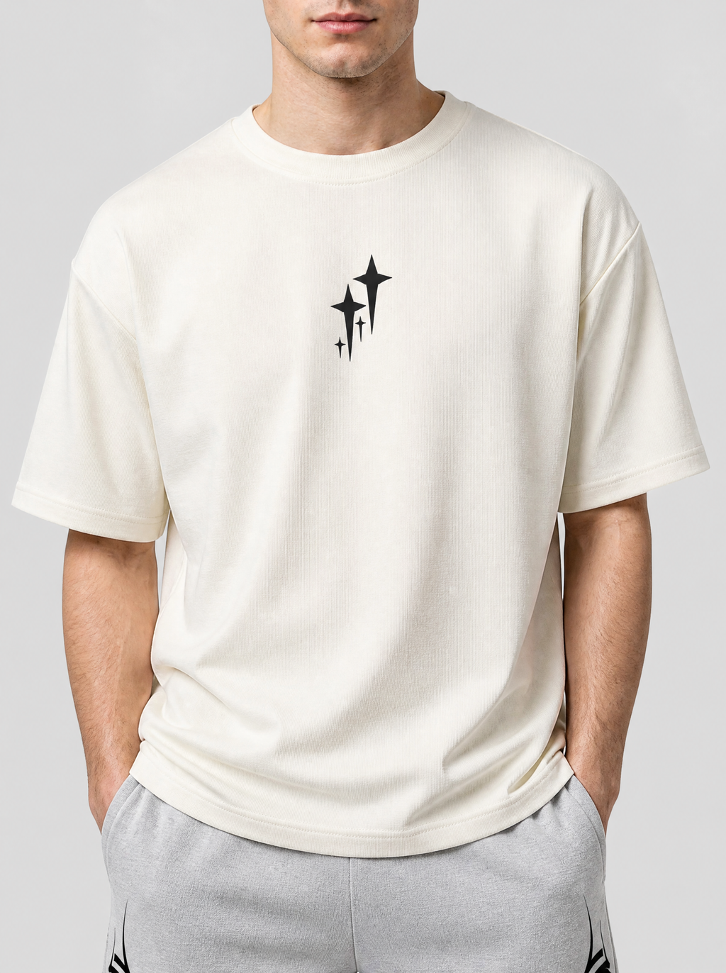 Photo détail | Gros plan sur le petit motif d’étoiles scintillantes noires au centre de la poitrine du t-shirt crème | Variante : Blanc