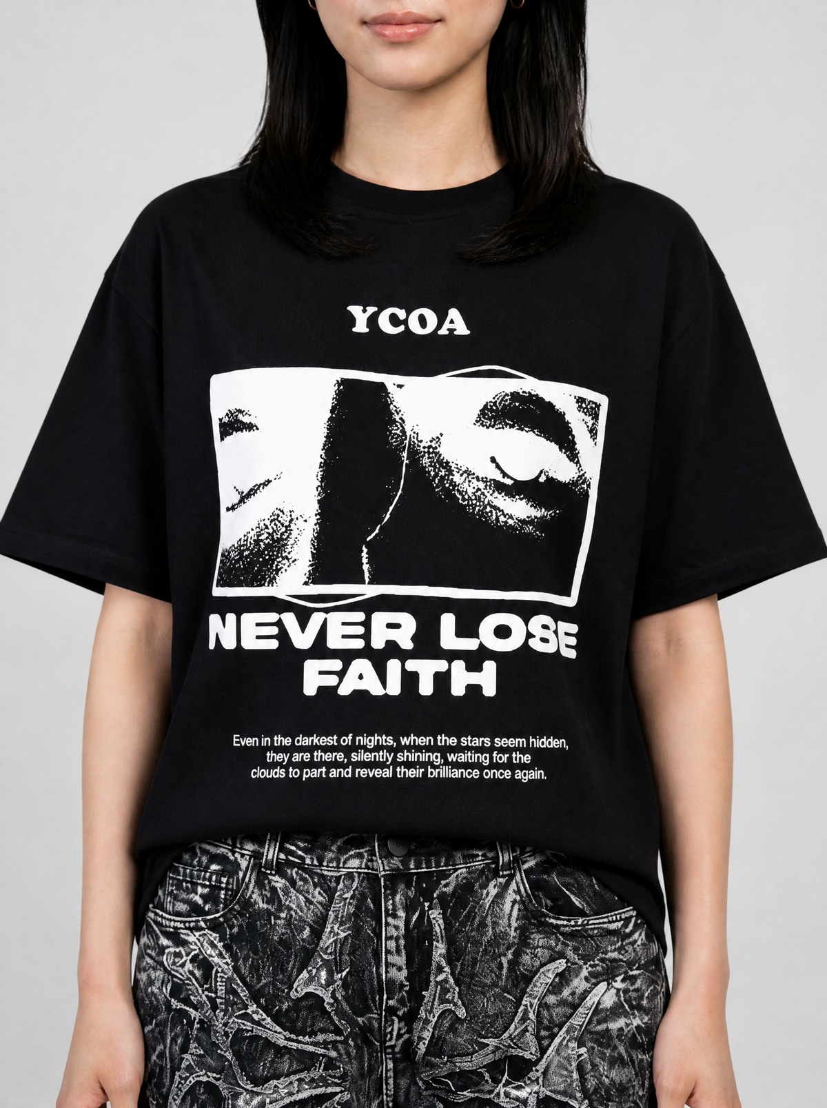 Photo détail | Gros plan sur l'imprimé blanc du t-shirt noir : regard en photo tramée encadrée et slogan Never Lose Faith | Variante : Noir