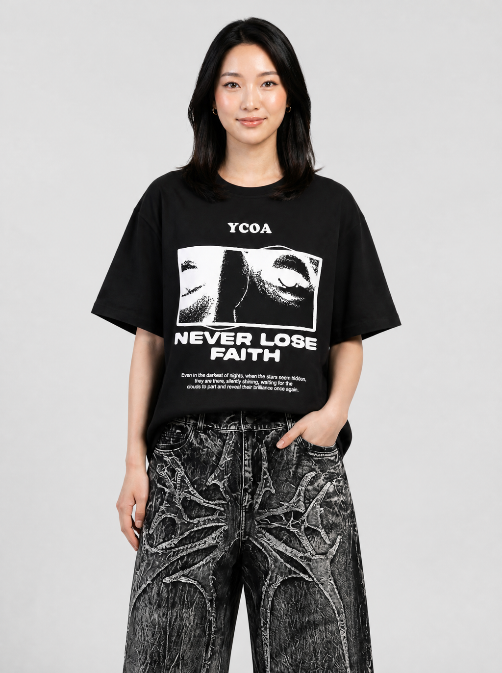 Autre vue | Femme de face en t-shirt noir imprimé blanc avec visage en trame et slogan Never Lose Faith, avec un jean noir délavé | Variante : Noir