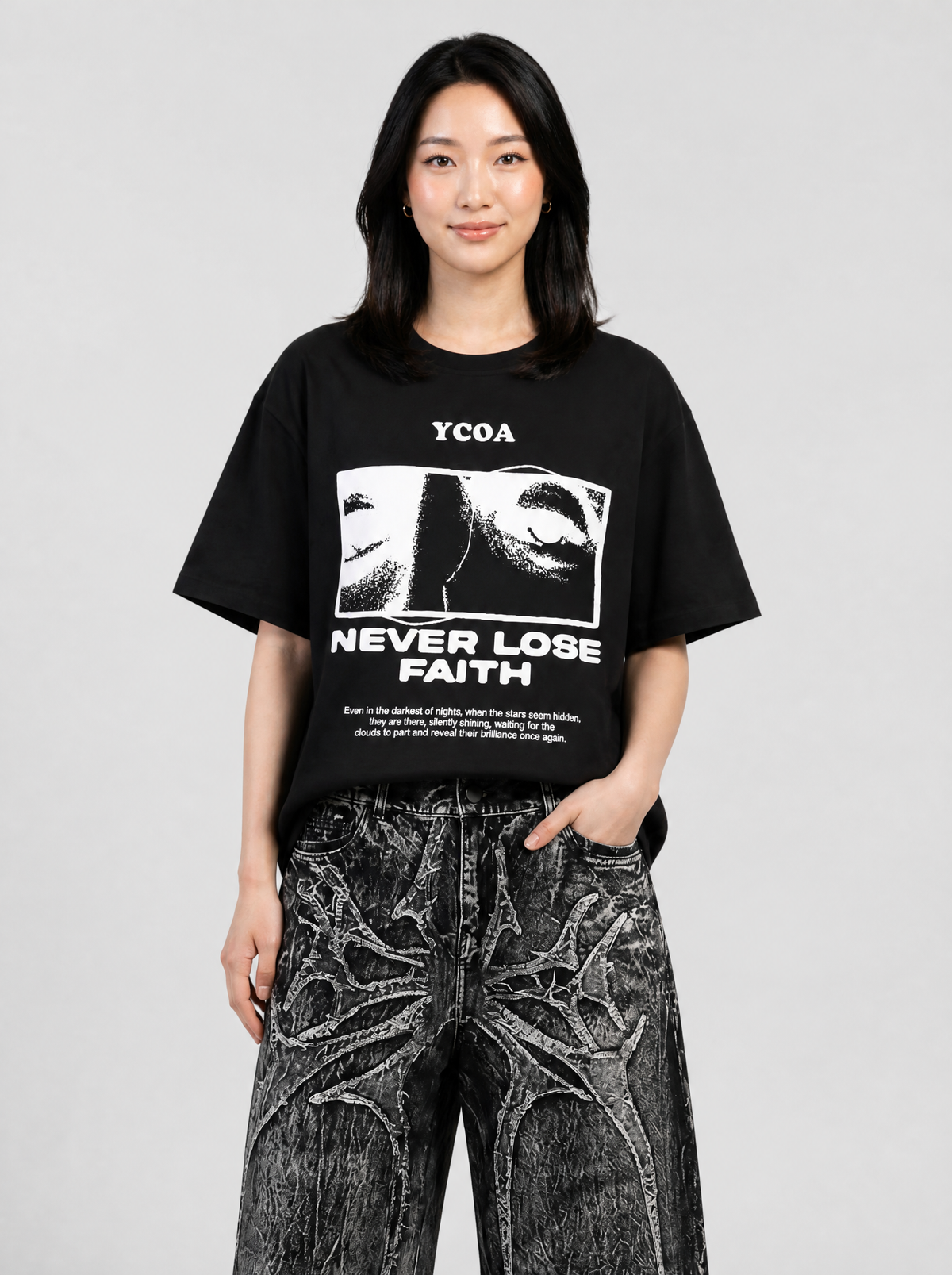 Autre vue | Femme de face en t-shirt noir imprimé blanc avec visage en trame et slogan Never Lose Faith, avec un jean noir délavé | Variante : Noir