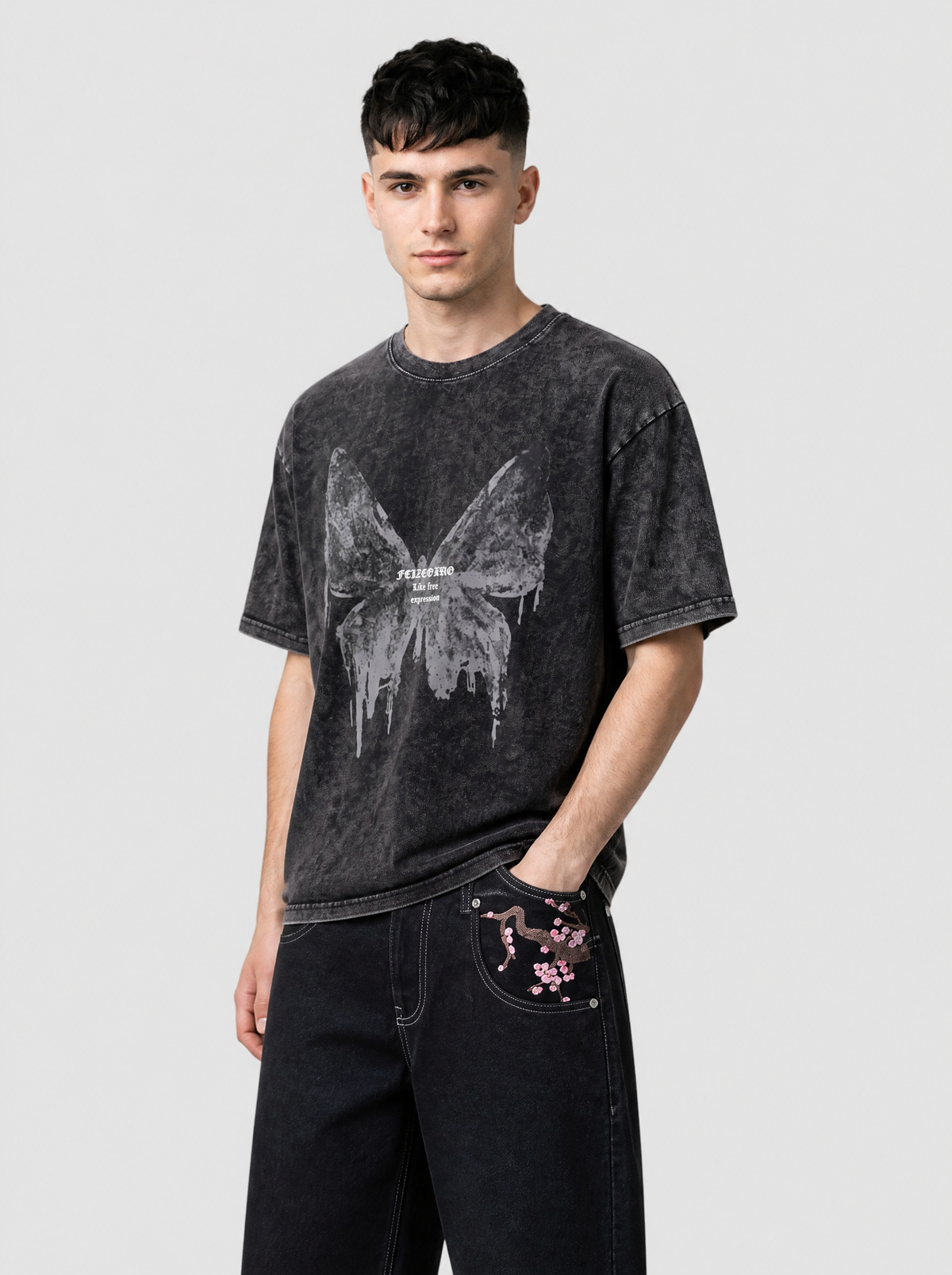 Autre vue | T-shirt oversize noir délavé à grand papillon gris dégoulinant porté de trois quarts avec un jean brut brodé