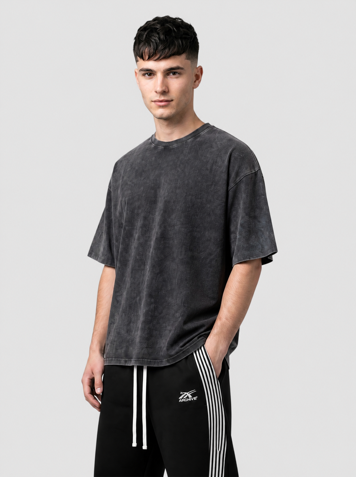 Autre vue | Homme portant le t-shirt oversize uni noir délavé à l’acide, vu de trois quarts avec un jogging noir à bandes | Variante : Noir