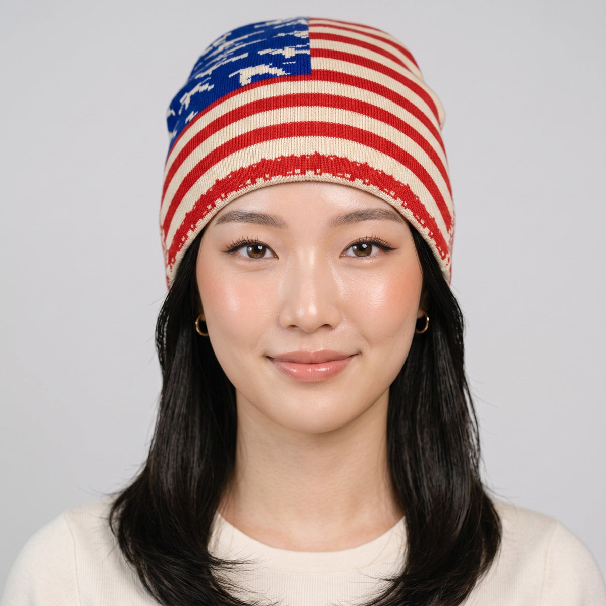 Bonnet drapeau USA à motif étoiles et rayures, porté par un modèle sur fond gris clair.