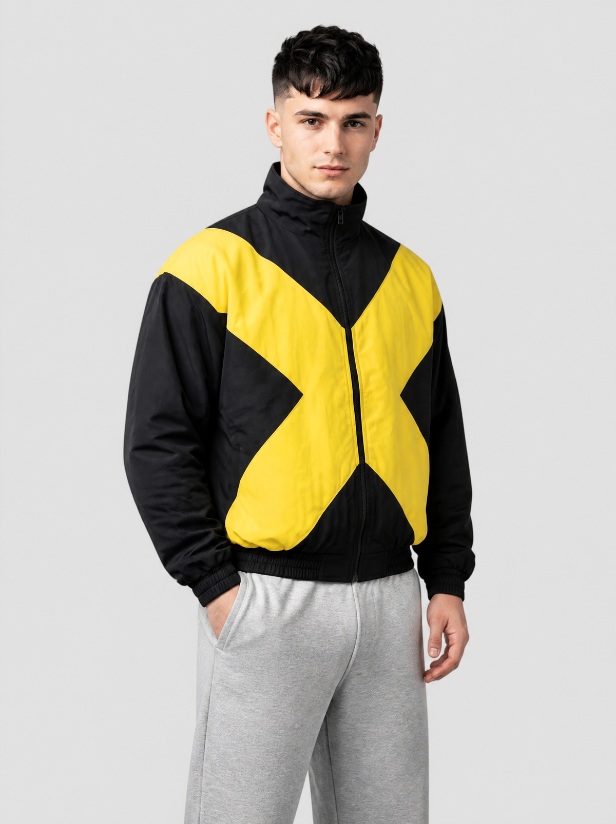 Autre vue | Bomber noir rembourré à grand X jaune vif sur le devant, porté de trois quarts avec un jogging gris