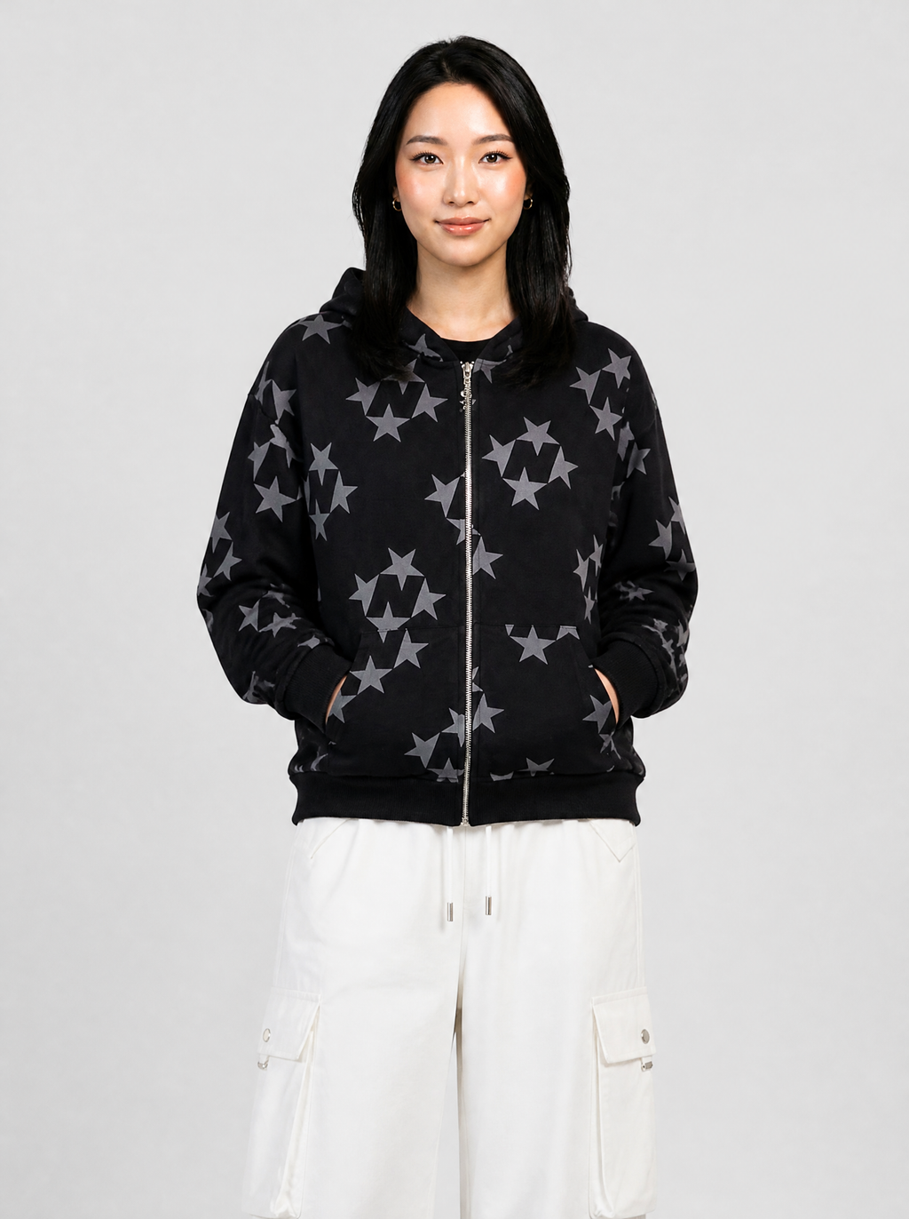 Autre vue | Femme de face en veste zippée à capuche noire imprimée d'étoiles grises en groupes, portée avec un pantalon cargo blanc | Variante : Noir