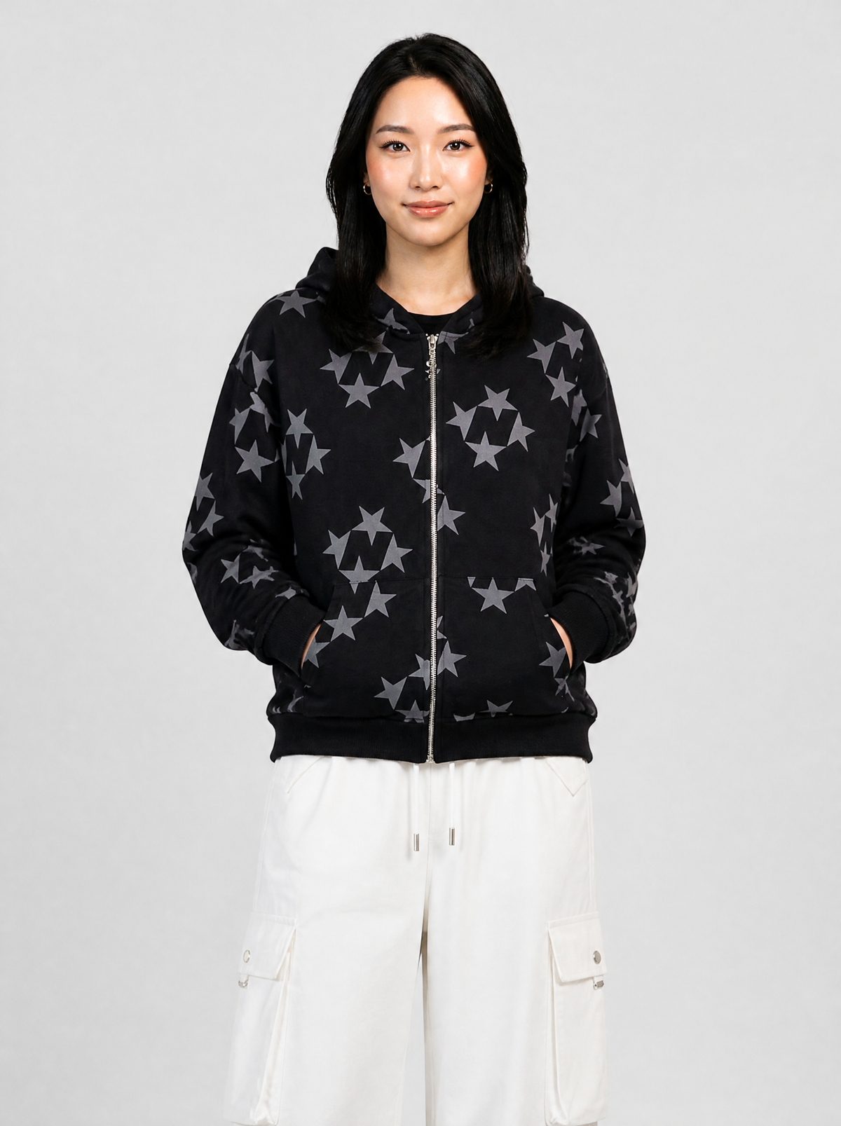 Autre vue | Femme de face en veste zippée à capuche noire imprimée d'étoiles grises en groupes, portée avec un pantalon cargo blanc | Variante : Noir