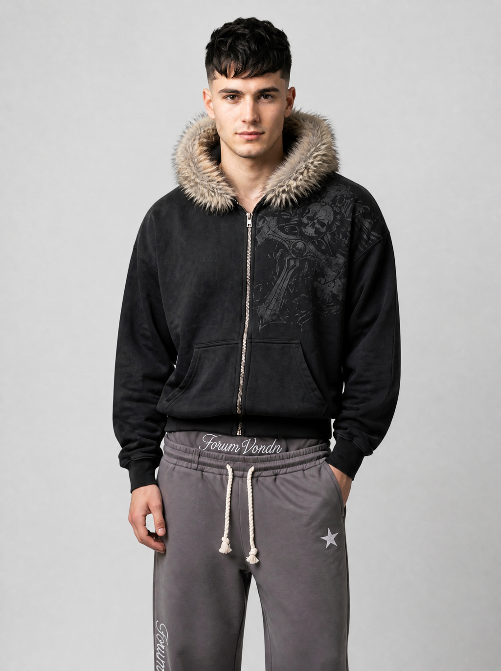 Autre vue | Homme de face en veste zippée noire capuche fausse fourrure relevée, imprimé gothique à l'épaule, avec un jogging gris | Variante : Noir