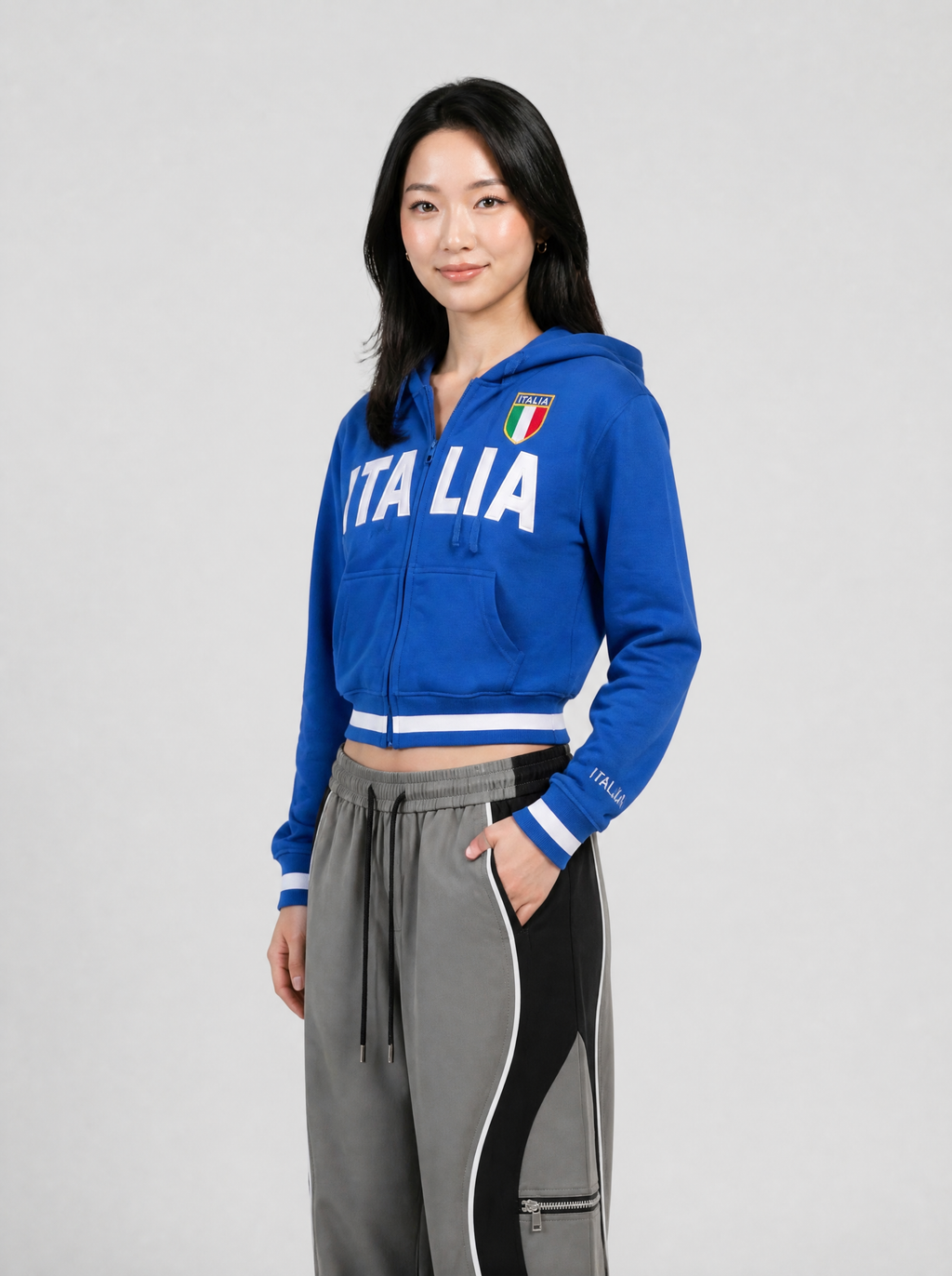 Autre vue | Femme de trois quarts en sweat zippé court bleu roi inscrit Italia et écusson tricolore, avec un pantalon gris à bandes