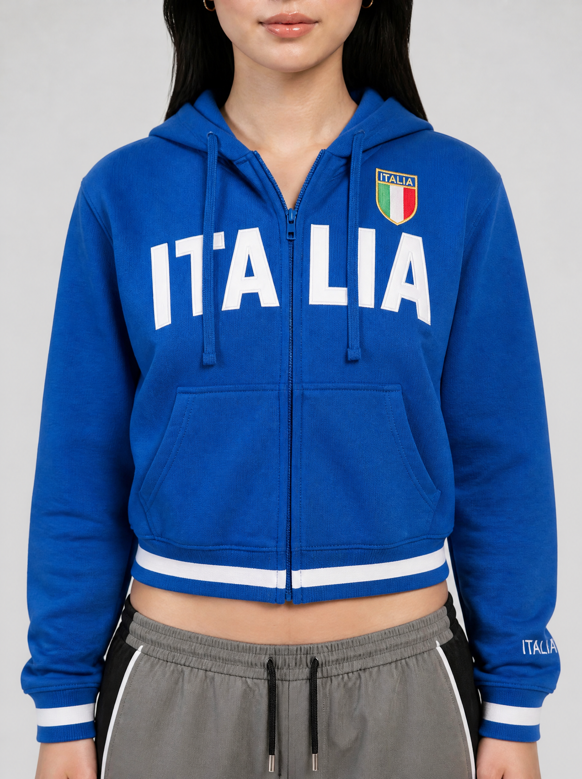 Photo détail | Gros plan sur le sweat bleu roi : lettres blanches Italia coupées par le zip et écusson vert blanc rouge sur la poitrine