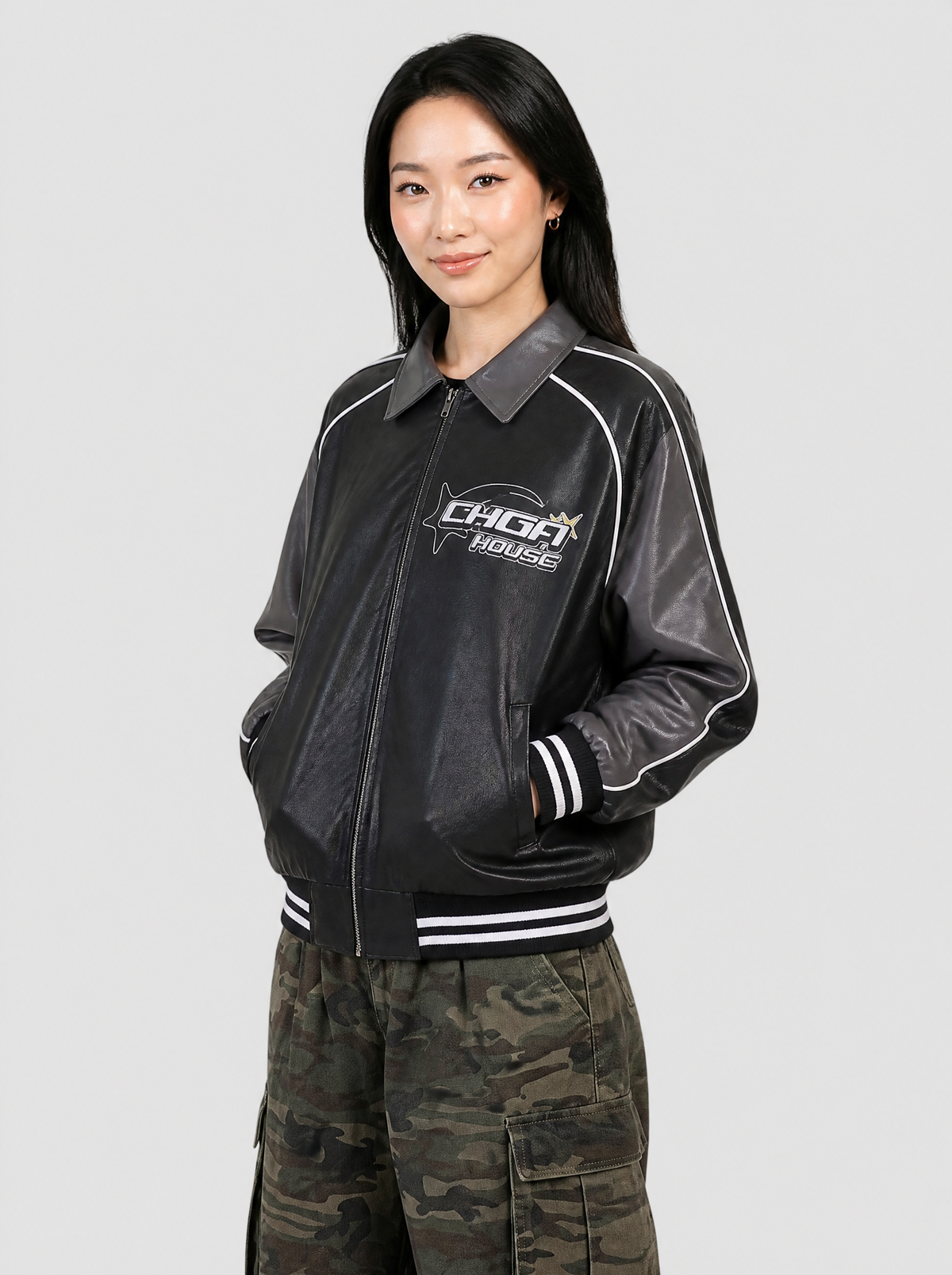 Autre vue | Femme portant la veste racing en simili cuir noir et gris à passepoils blancs, vue de trois quarts avec un cargo
