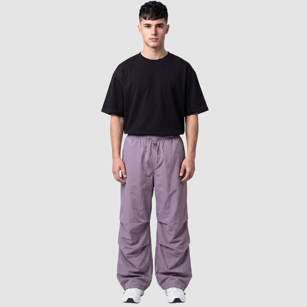 Modèle portant un pantalon parachute violet mat taille haute avec genoux froncés et cordons ajustables.